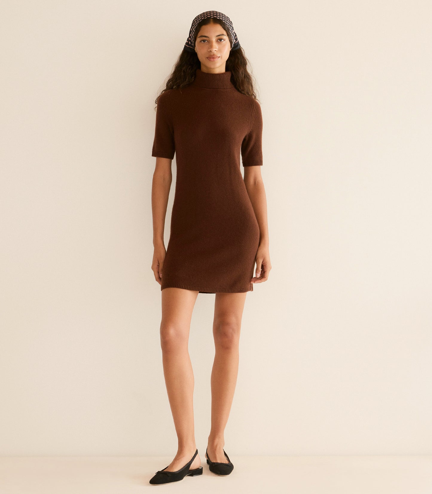Woman wearing a brown dress against a beige background