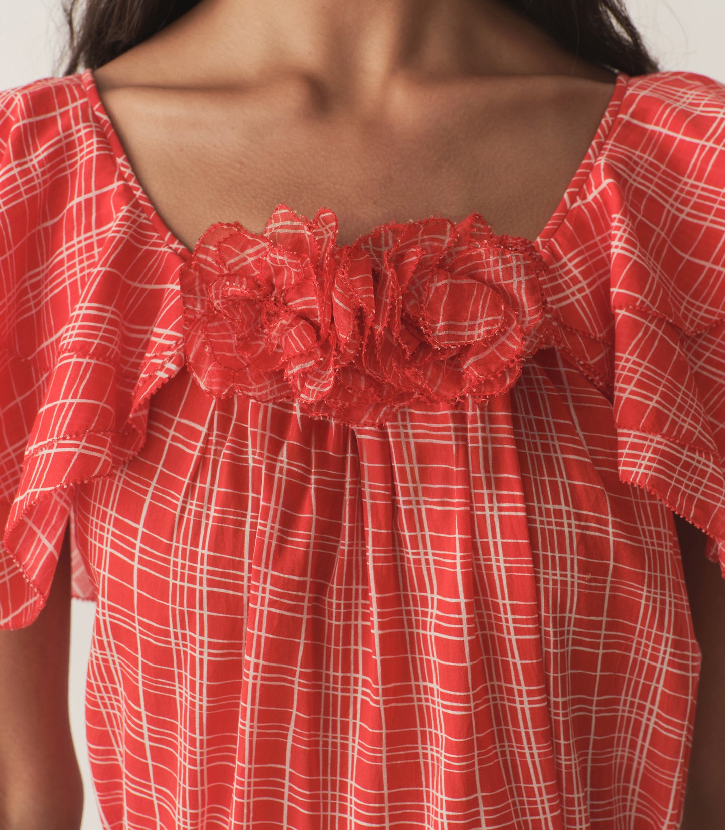 Rocio is wearing a red plaid top with ruffled sleeves, paired with black capris.