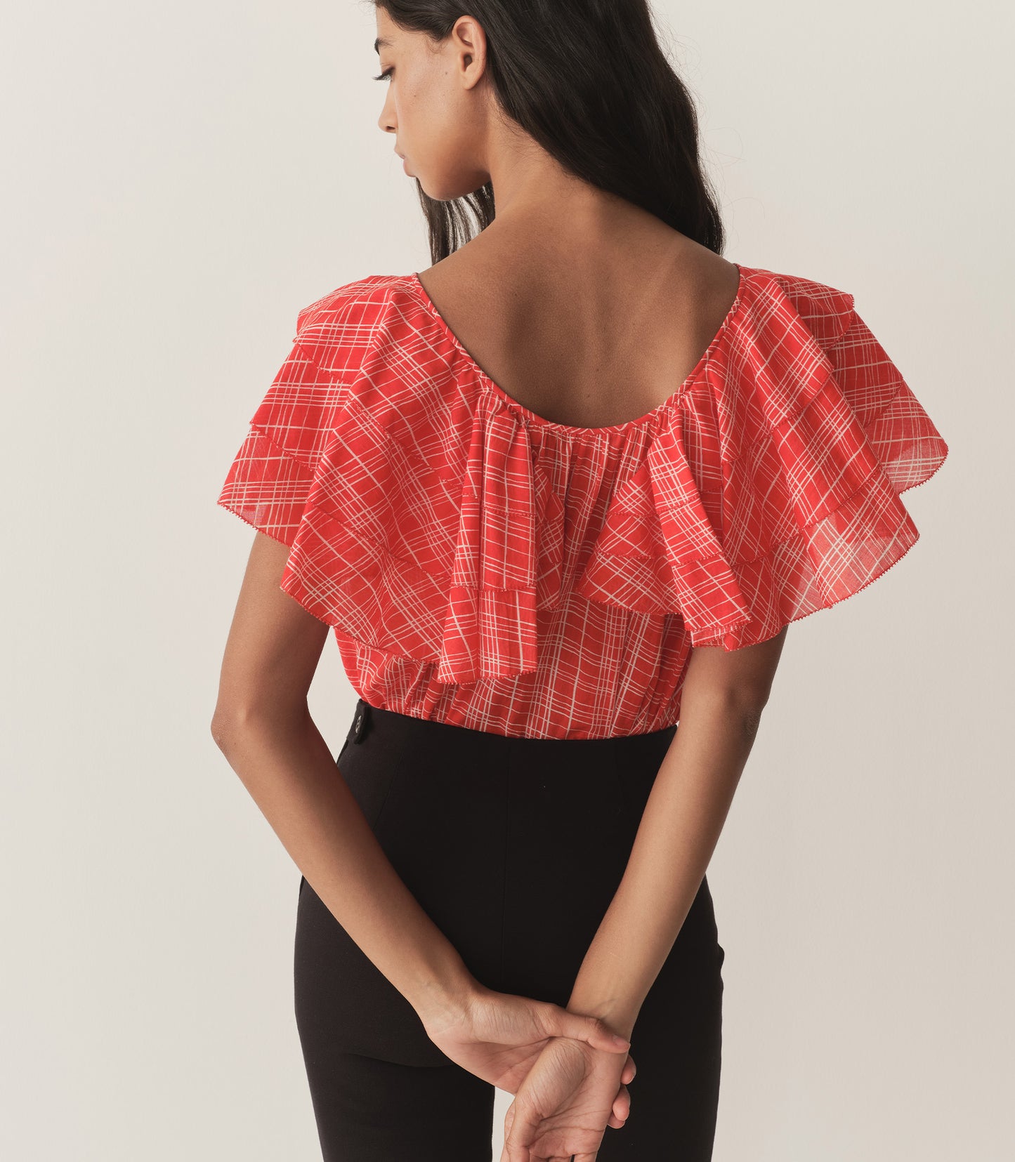Rocio is wearing a red plaid top with ruffled sleeves, paired with black capris.