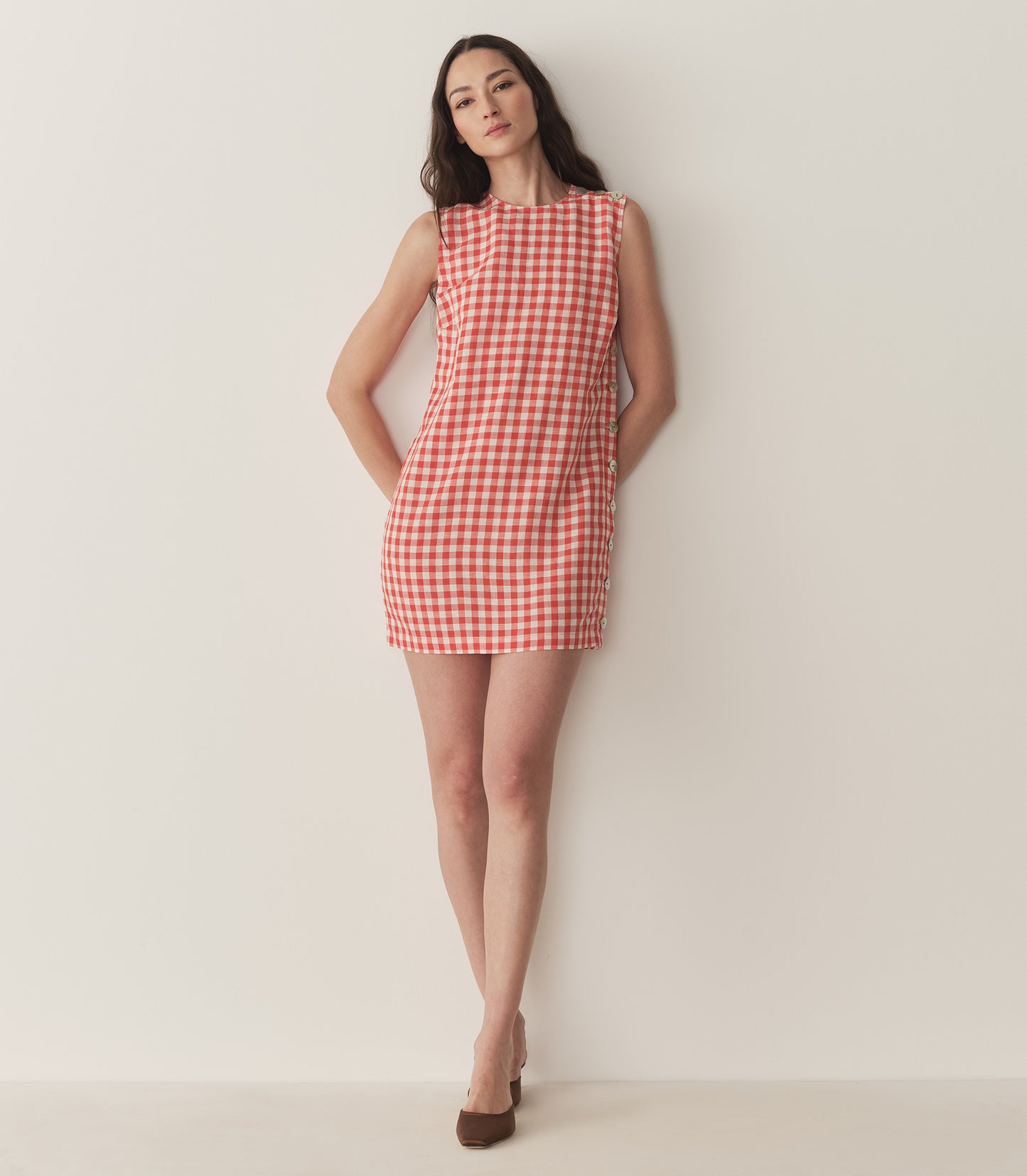 Bruna is wearing a red and white plaid sleeveless mini dress.