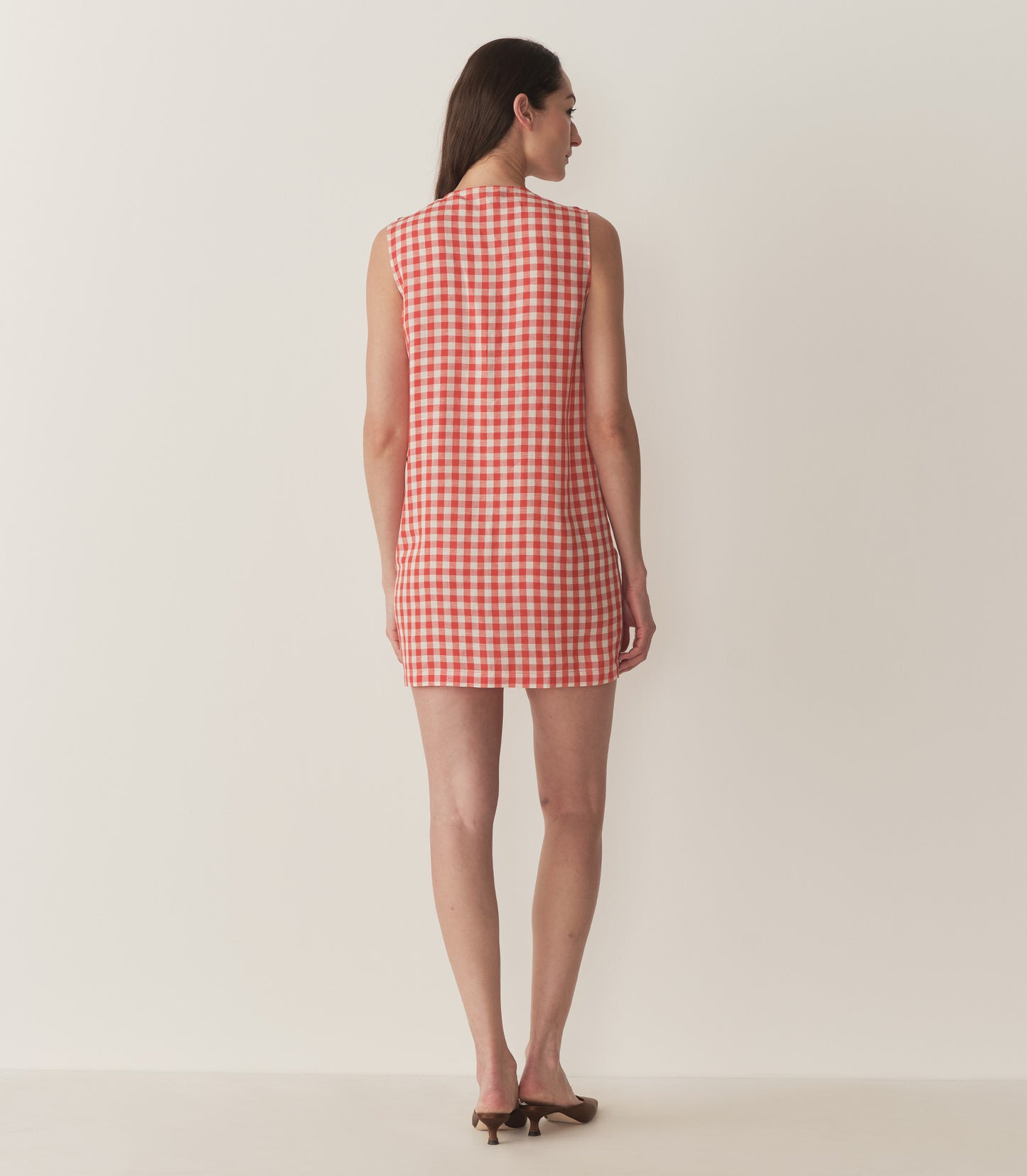 Bruna is wearing a red and white plaid sleeveless mini dress.