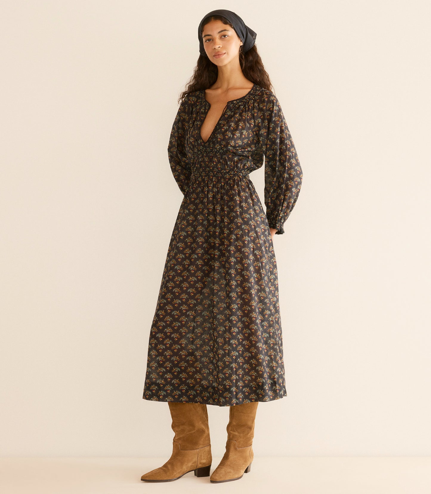 Woman wearing a floral dress with long sleeves, standing against a plain background.