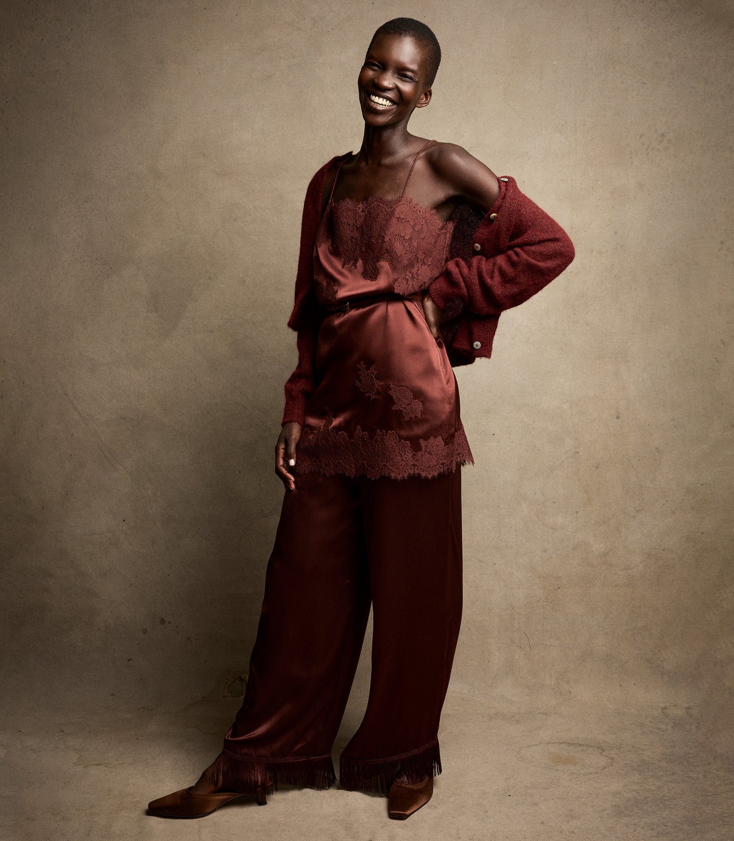 Person wearing a burgundy outfit against a beige background