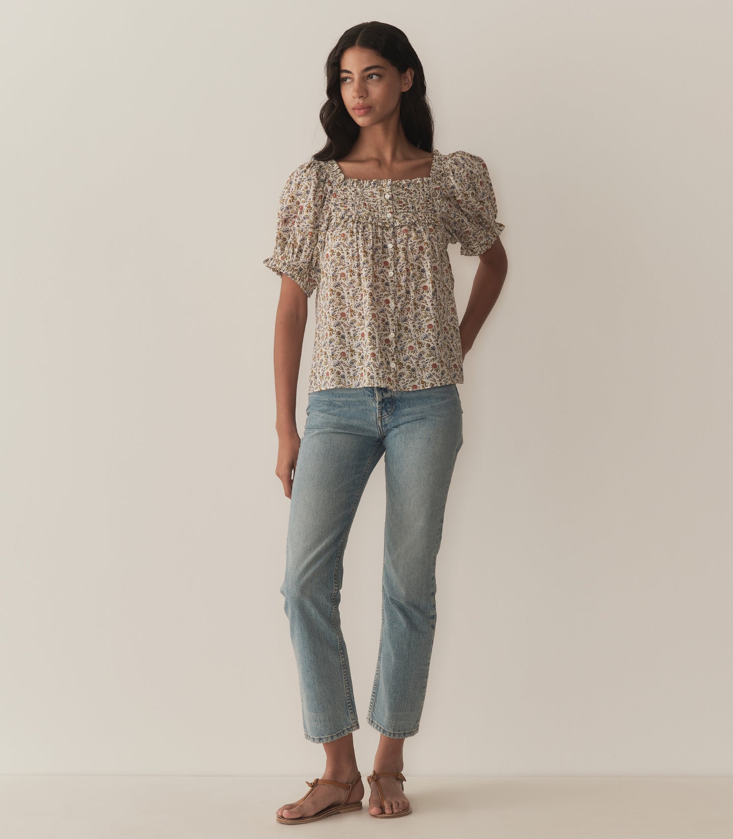 Rocio is wearing a floral top with short puff sleeves paired with jeans.