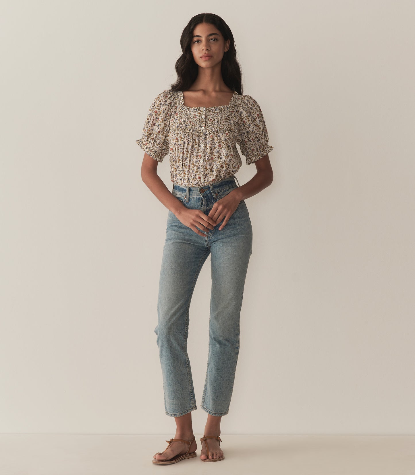 Rocio is wearing a floral top with short puff sleeves paired with jeans.