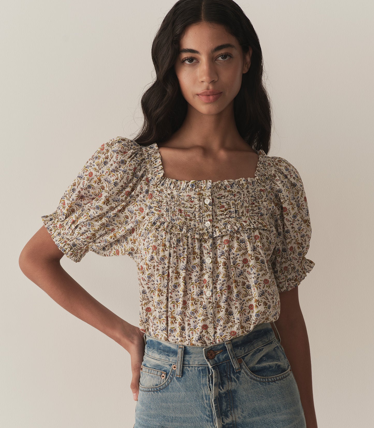 Rocio is wearing a floral top with short puff sleeves paired with jeans.