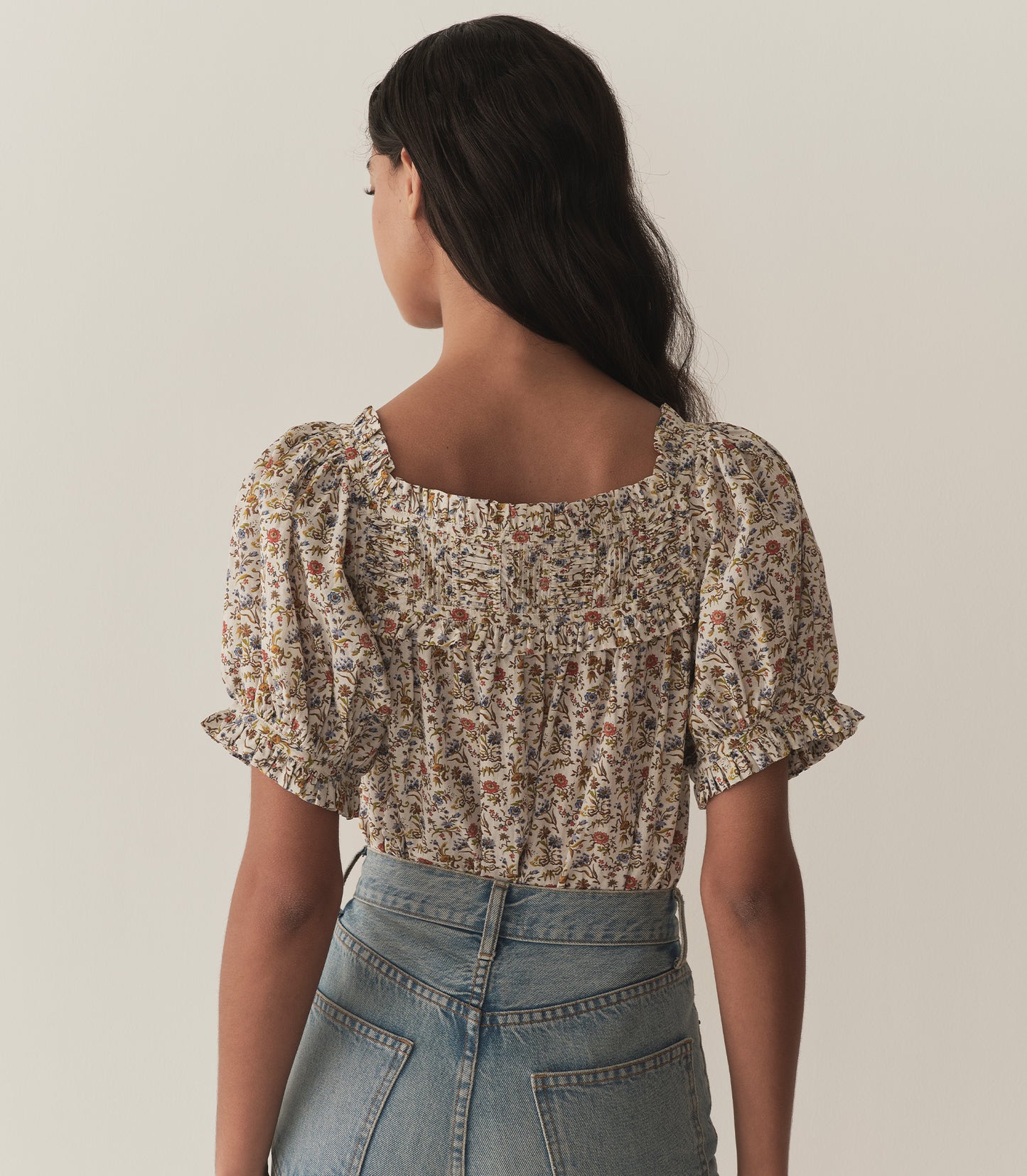 Rocio is wearing a floral top with short puff sleeves paired with jeans.