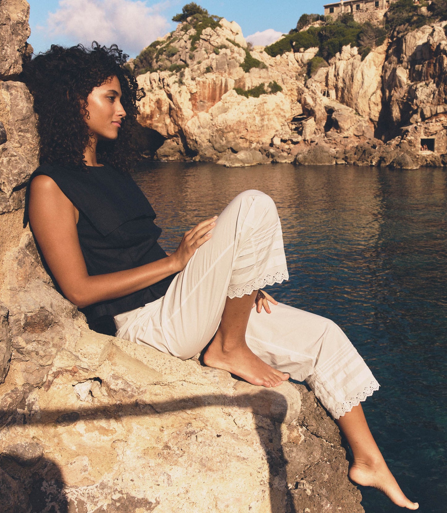 Melodie is wearing white pants and a black blouse.