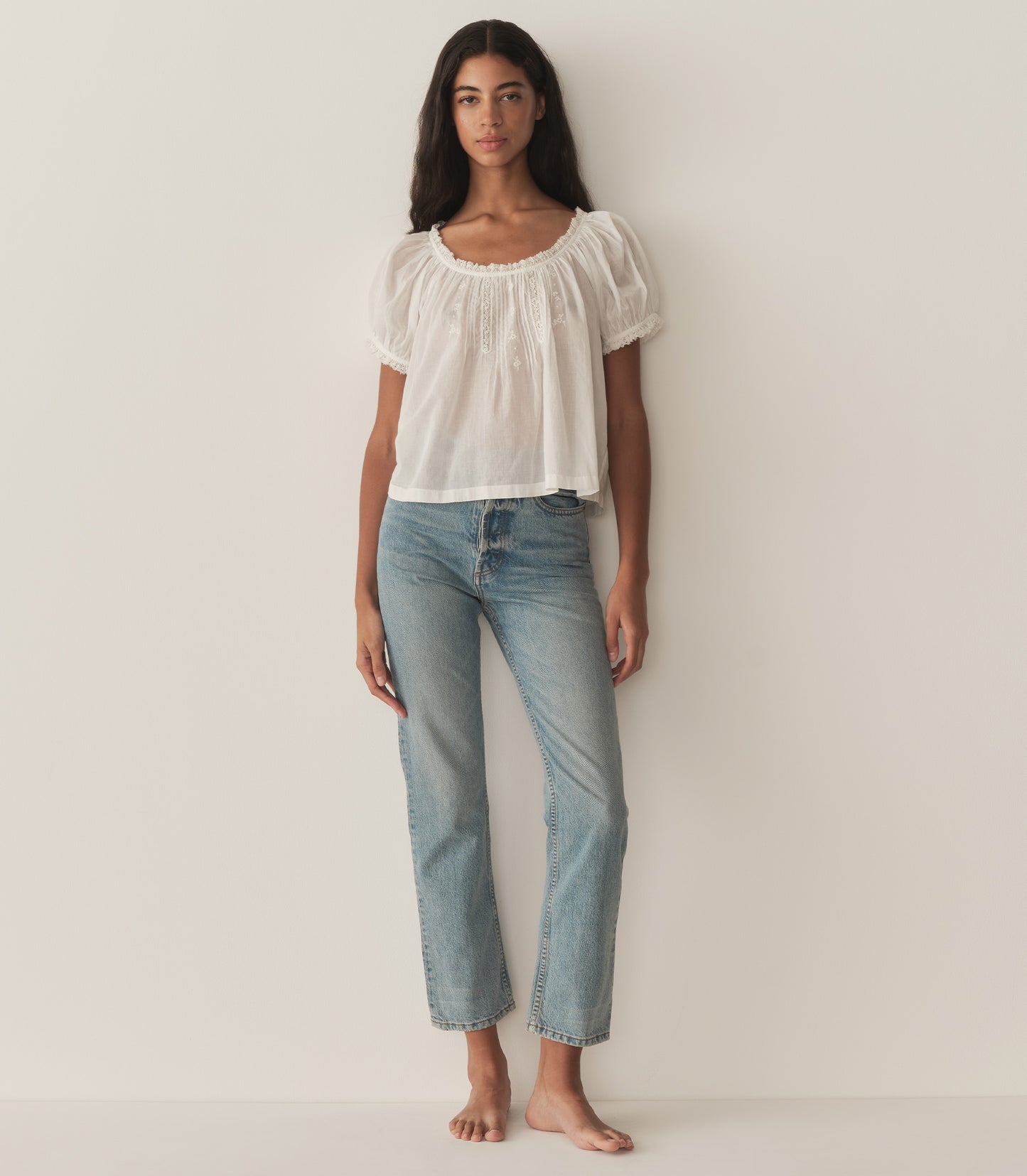 Rocio is wearing a white short puff sleeve blouse and denim jeans.