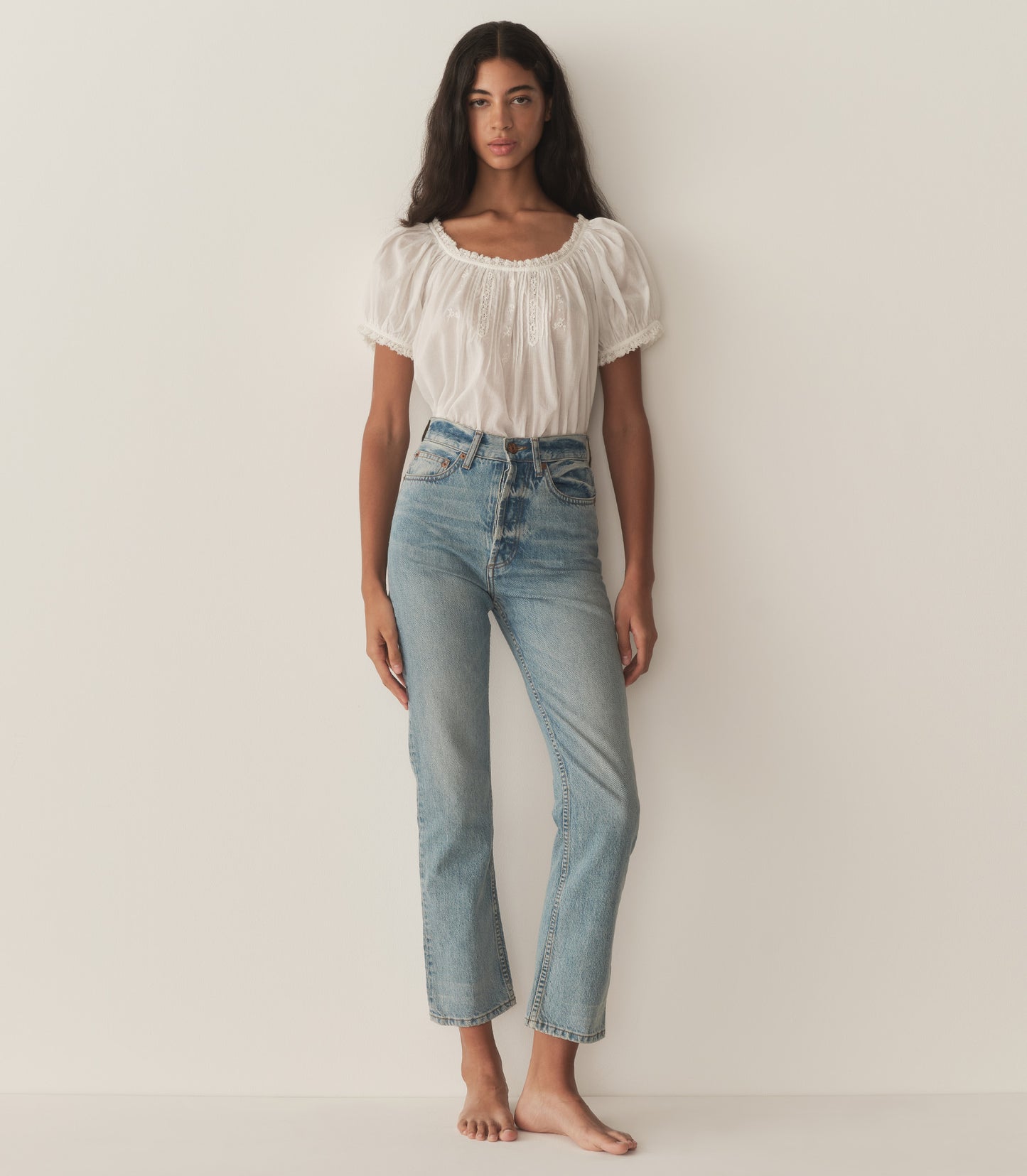 Rocio is wearing a white short puff sleeve blouse and denim jeans.