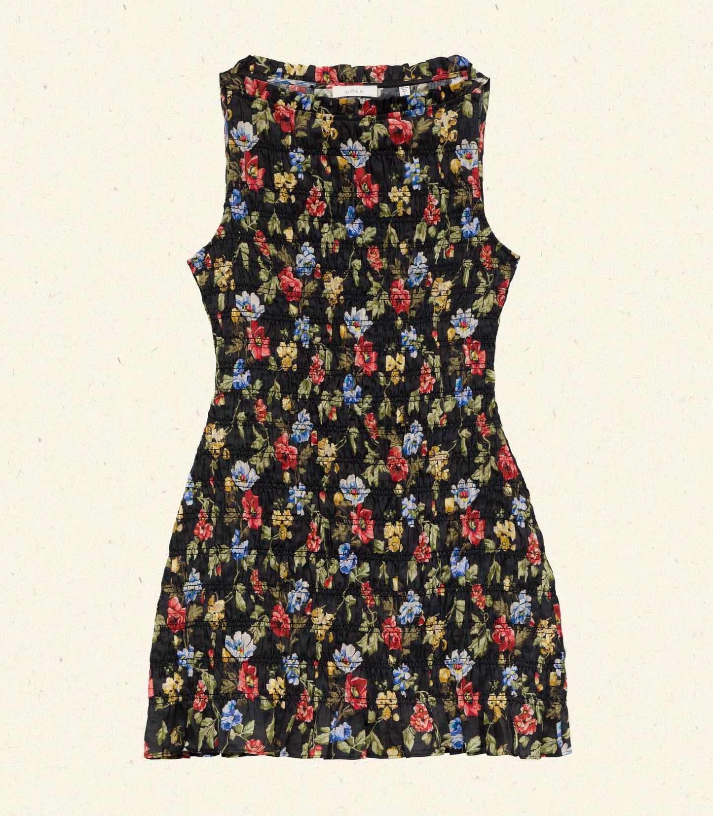 Melodie is wearing a black floral mini dress in front of a rustic background.