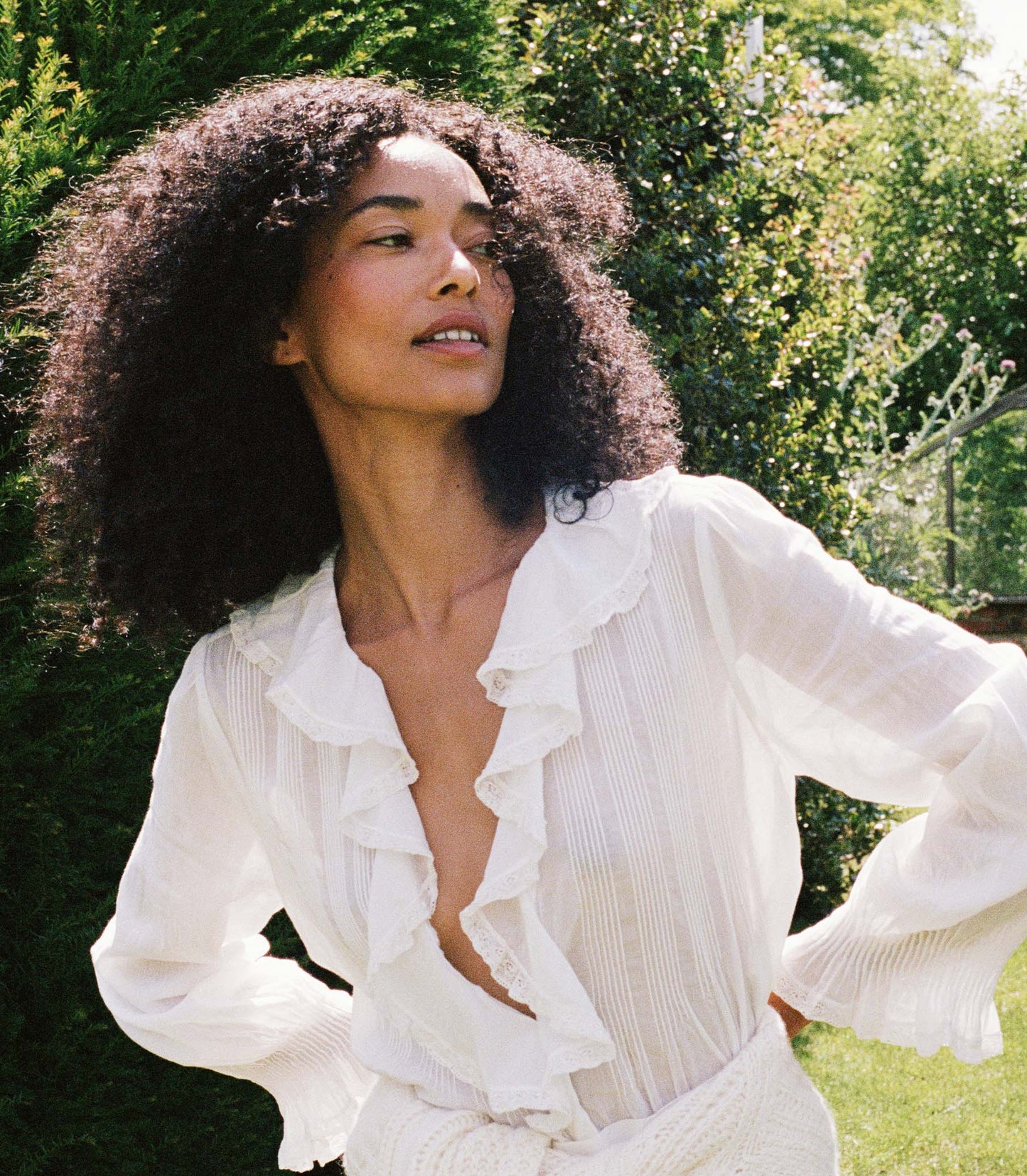 Woman wearing a white blouse and white skirt amongst greenery