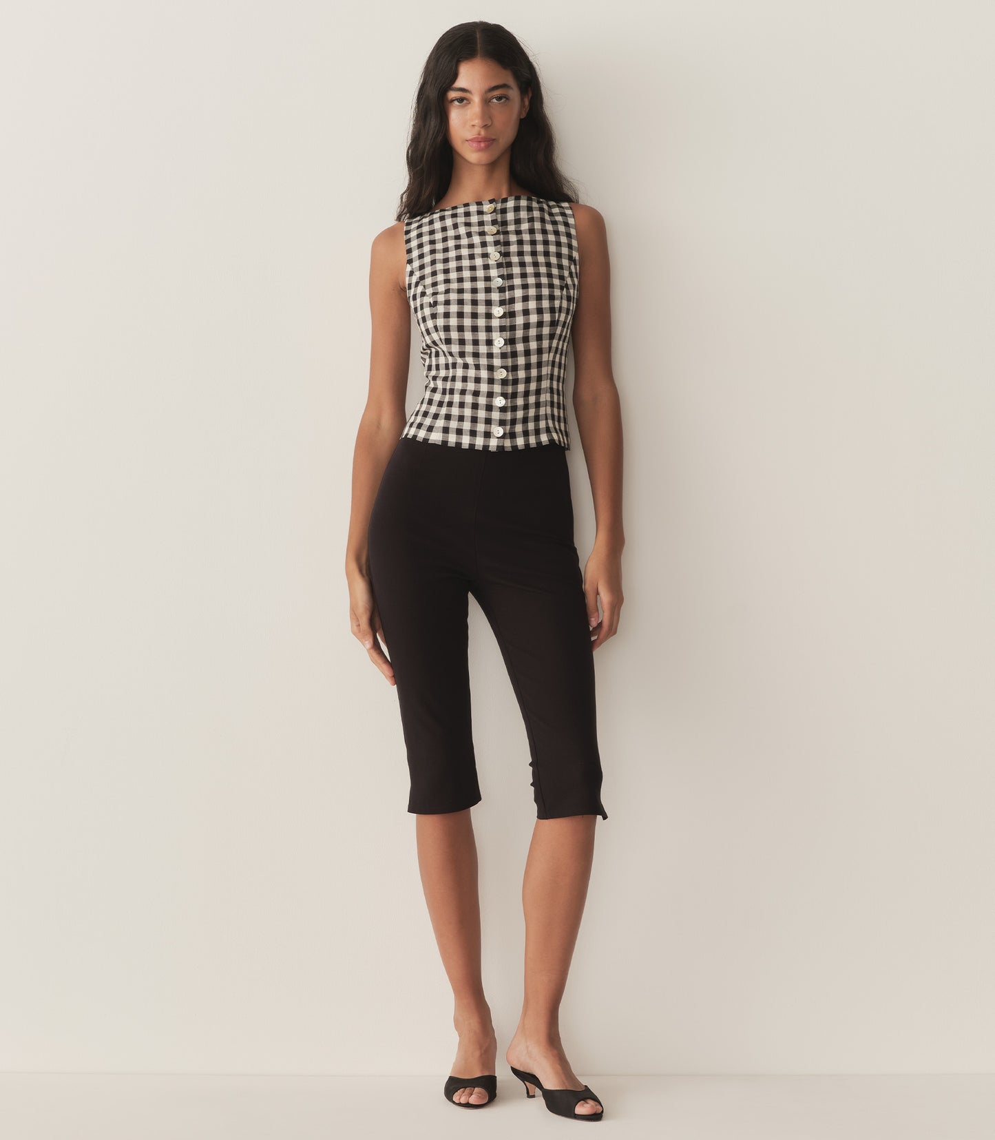 Rocio is wearing a sleeveless black and white gingham top with a matching bandana and black capris.