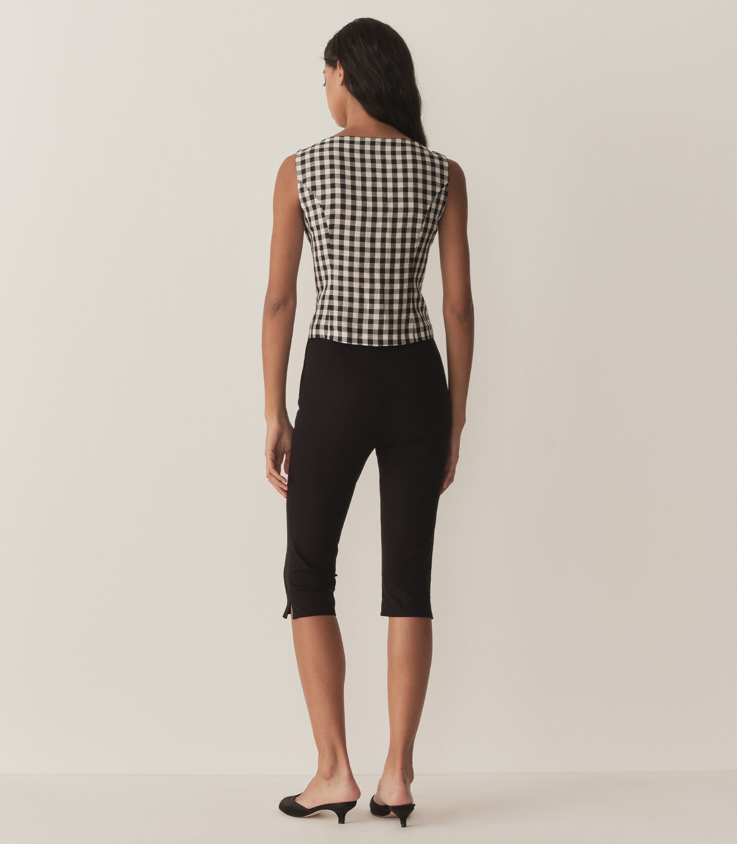 Rocio is wearing a sleeveless black and white gingham top with a matching bandana and black capris.