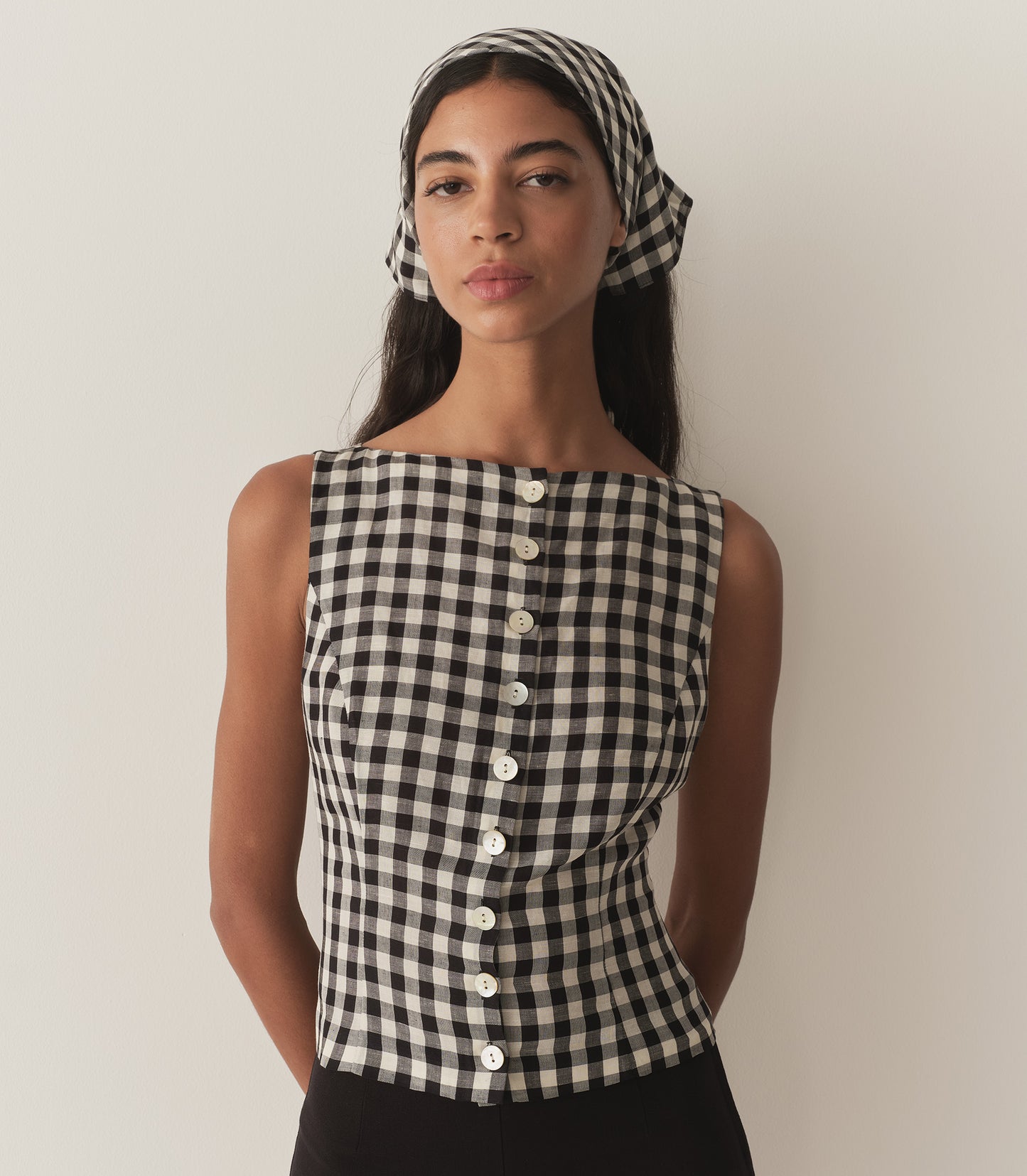 Rocio is wearing a sleeveless black and white gingham top with a matching bandana and black capris.