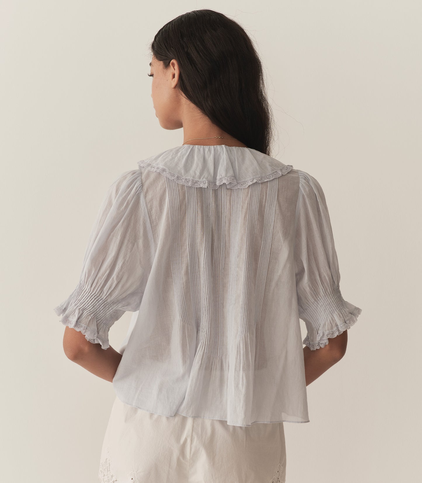 Rocio is wearing a light blue short sleeve ruffled blouse paired with white lace silk shorts.