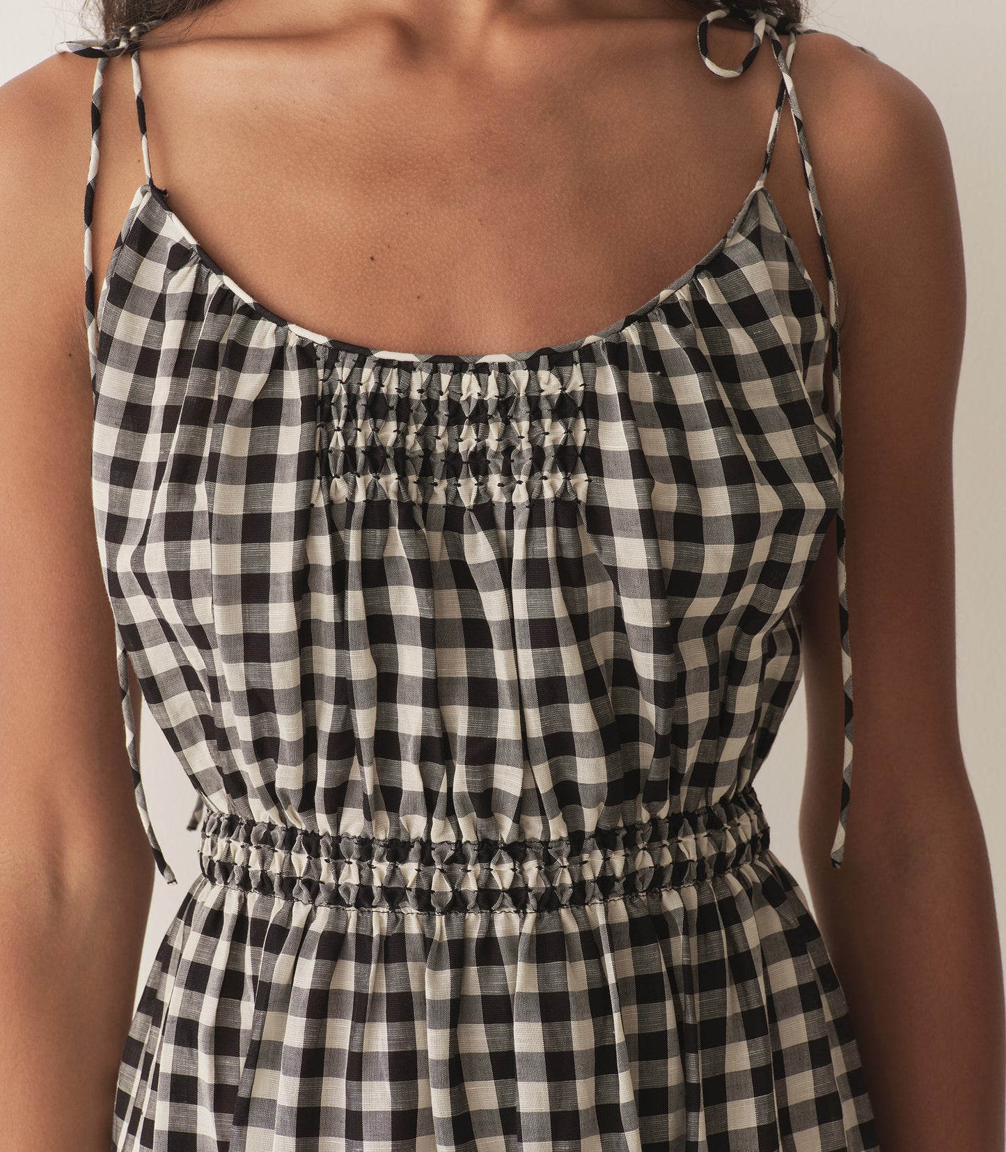 Rocio is wearing a mid-length black and white gingham dress with black flats.
