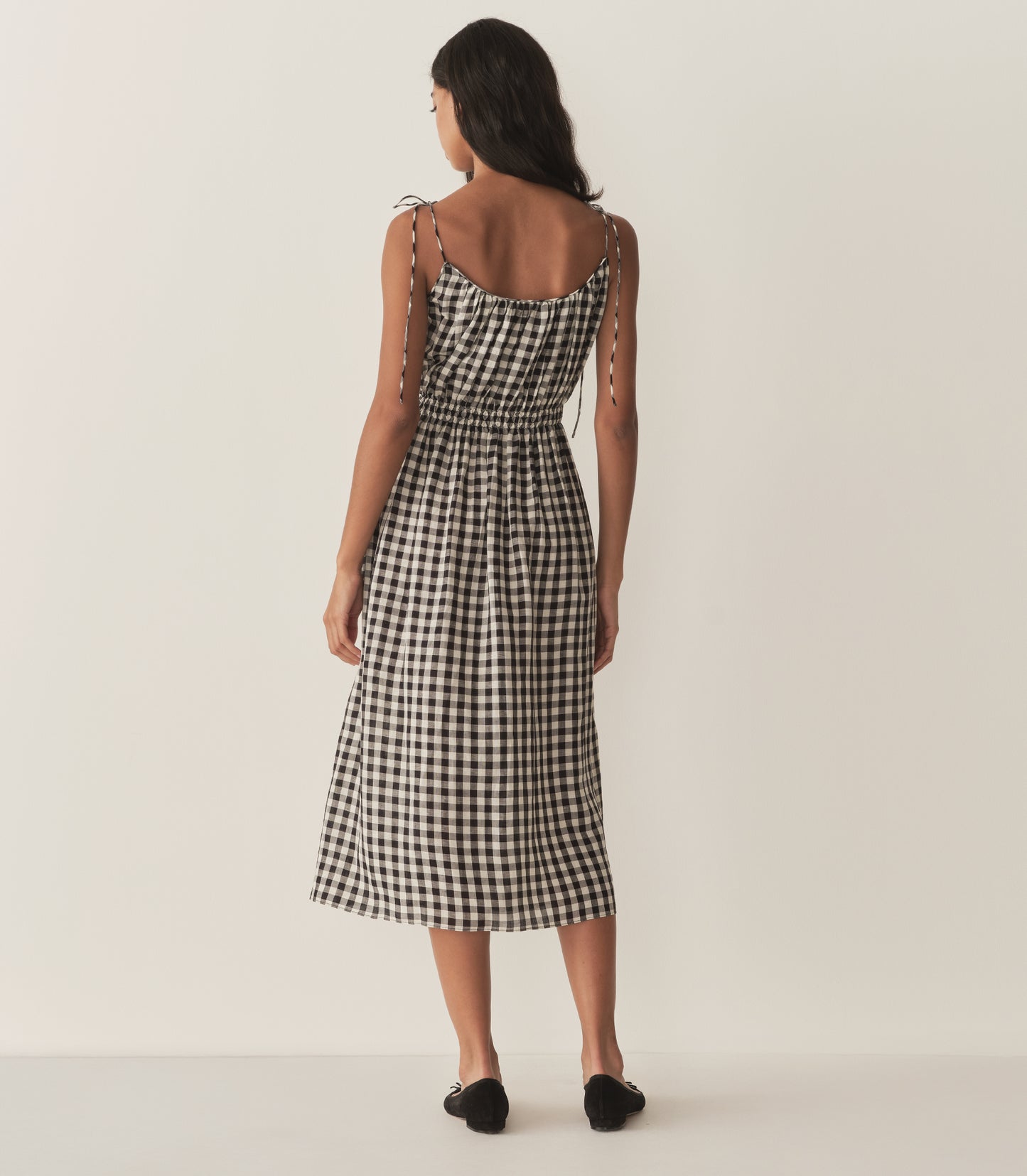 Rocio is wearing a mid-length black and white gingham dress with black flats.