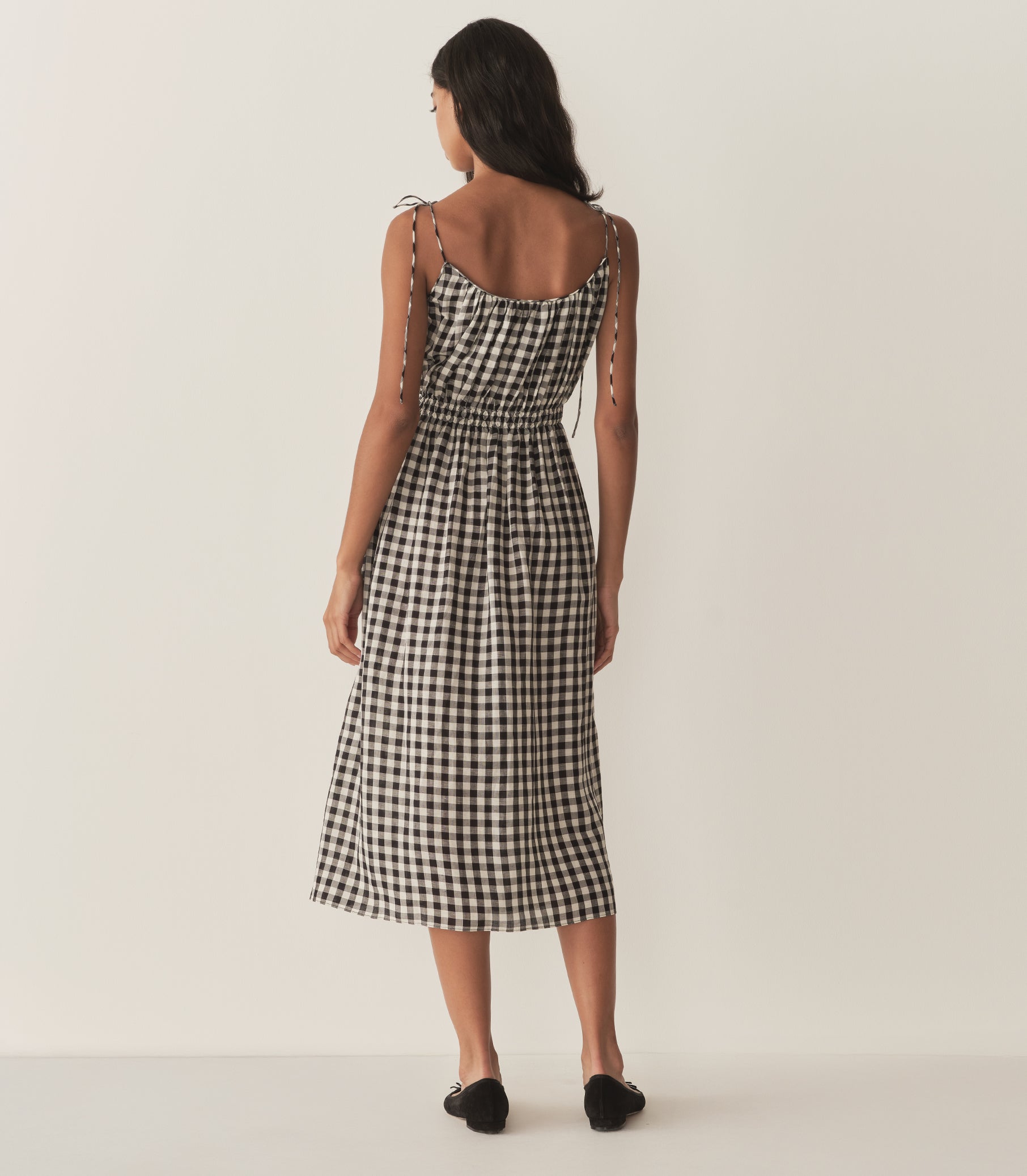 Rocio is wearing a mid-length black and white gingham dress with black flats. 4