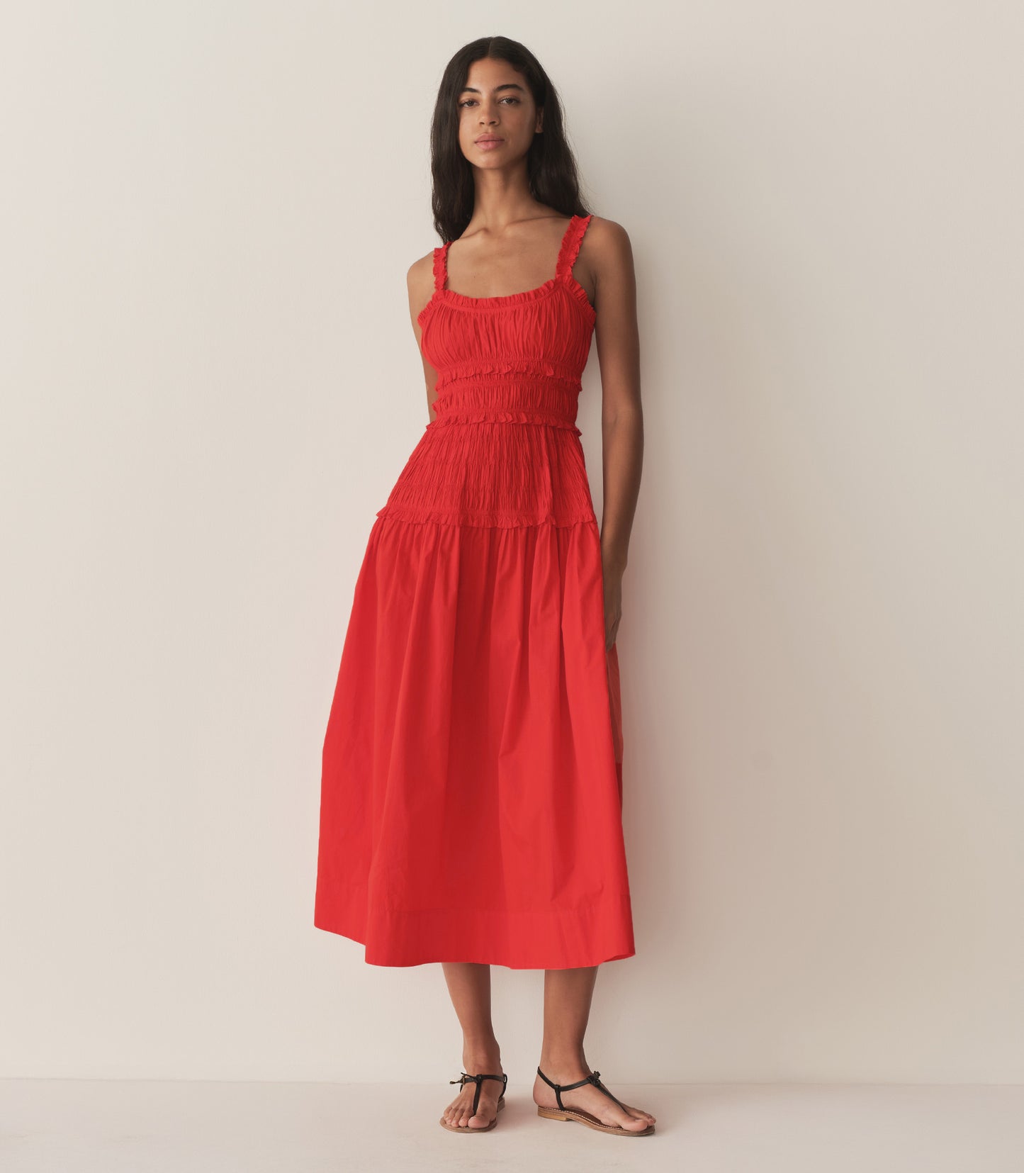 Rocio is wearing a red mid-length dress with sandals.
