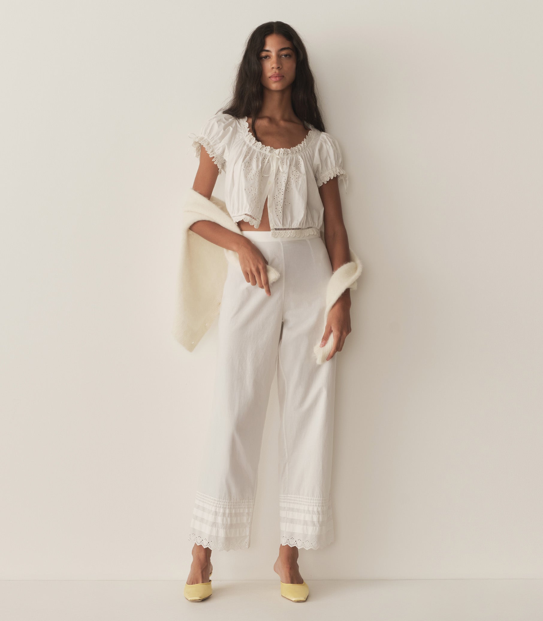 Rocio is wearing a white short puff sleeve top with white pants and yellow mule heels. 4