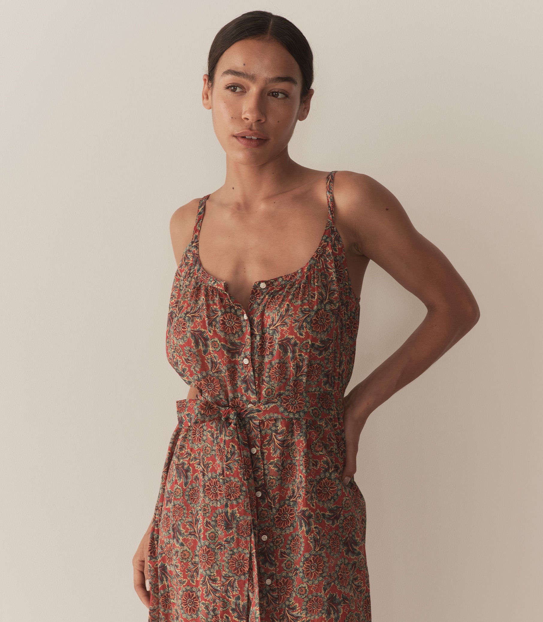 Zahara is wearing a sleeveless midi dress in an orange floral pattern, paired with sandals. 2