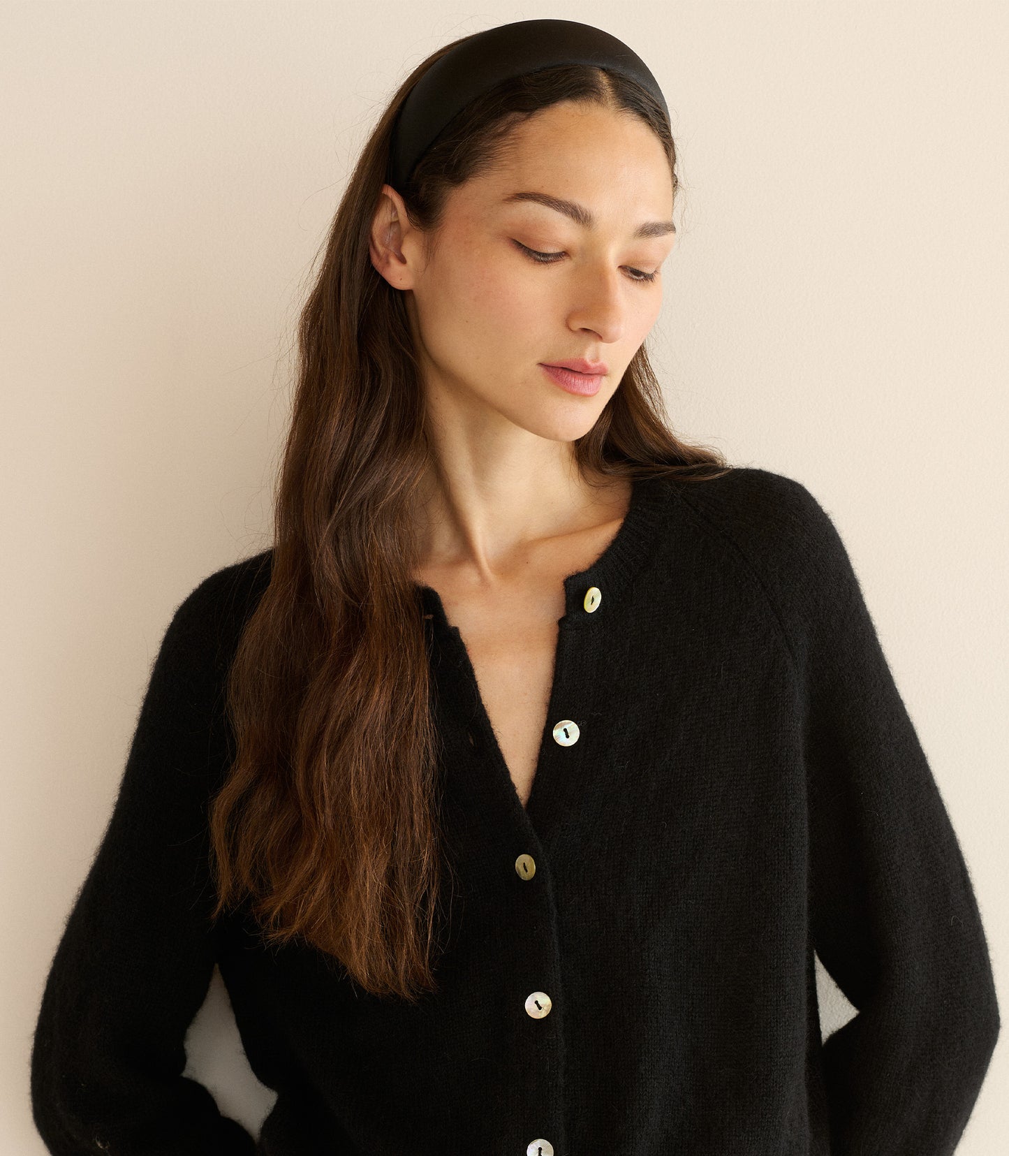 Woman wearing a black cardigan against a beige background