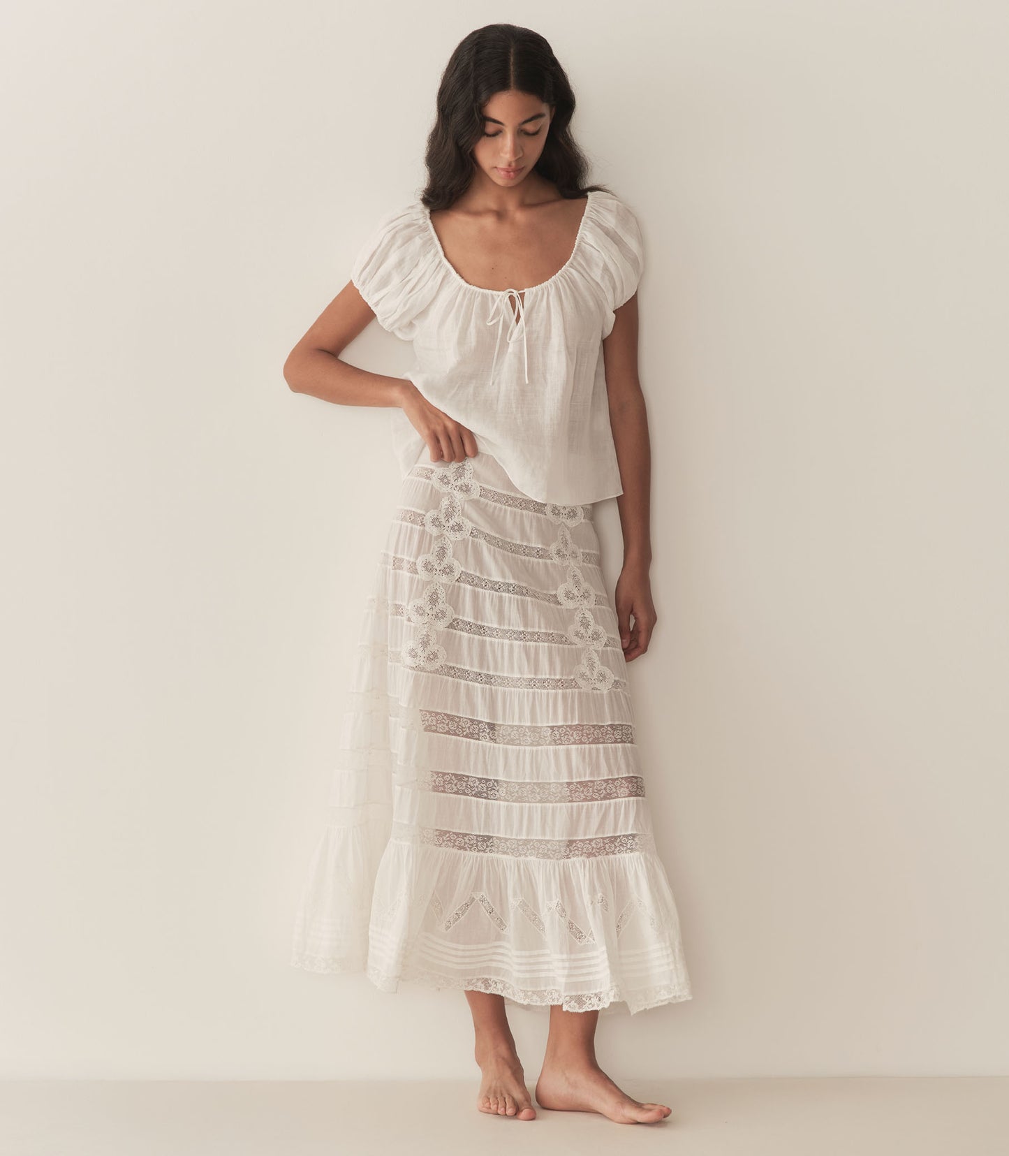 Rocio is wearing a white short puff sleeve blouse paired with a white maxi skirt.