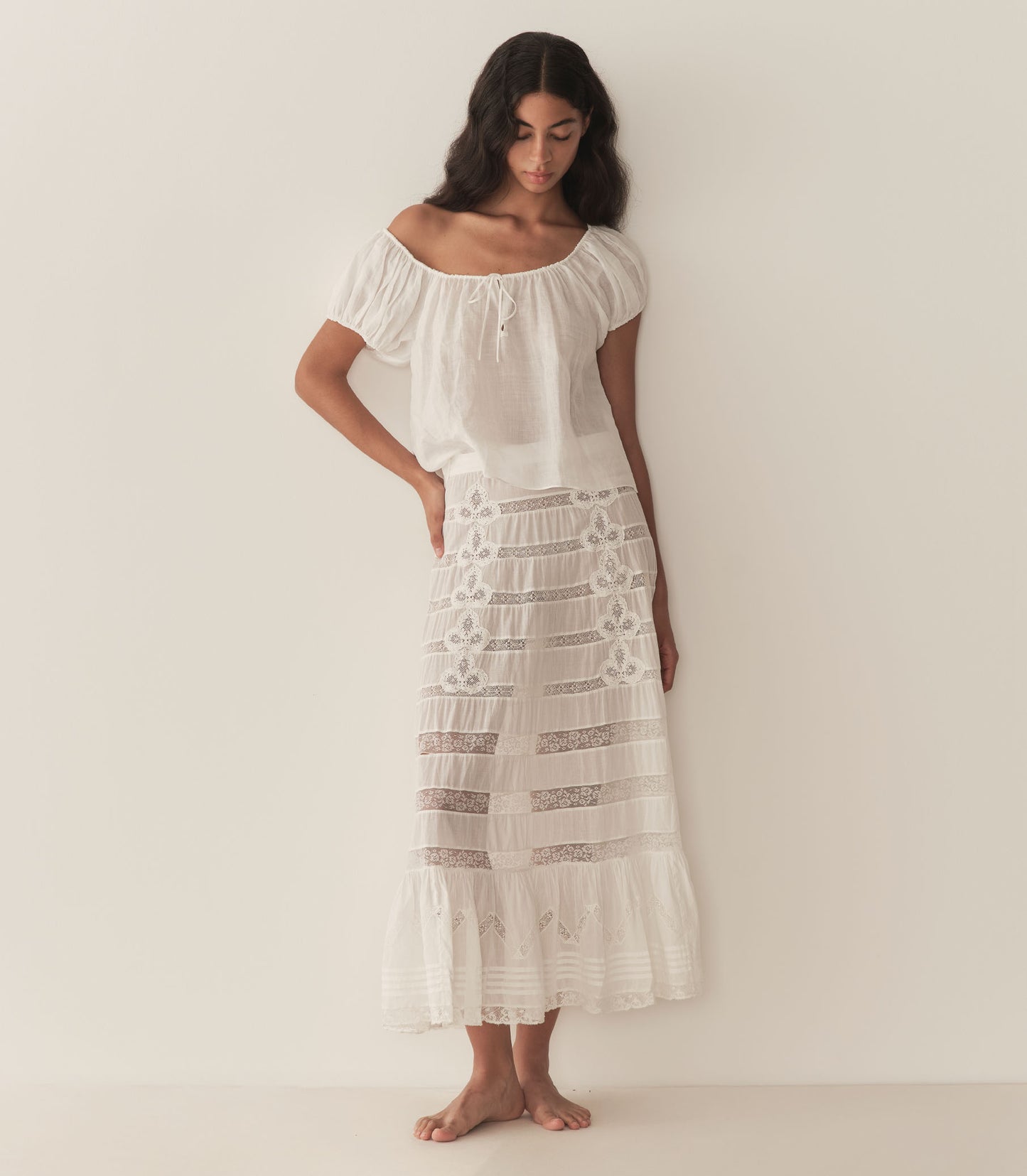 Rocio is wearing a white short puff sleeve blouse paired with a white maxi skirt.