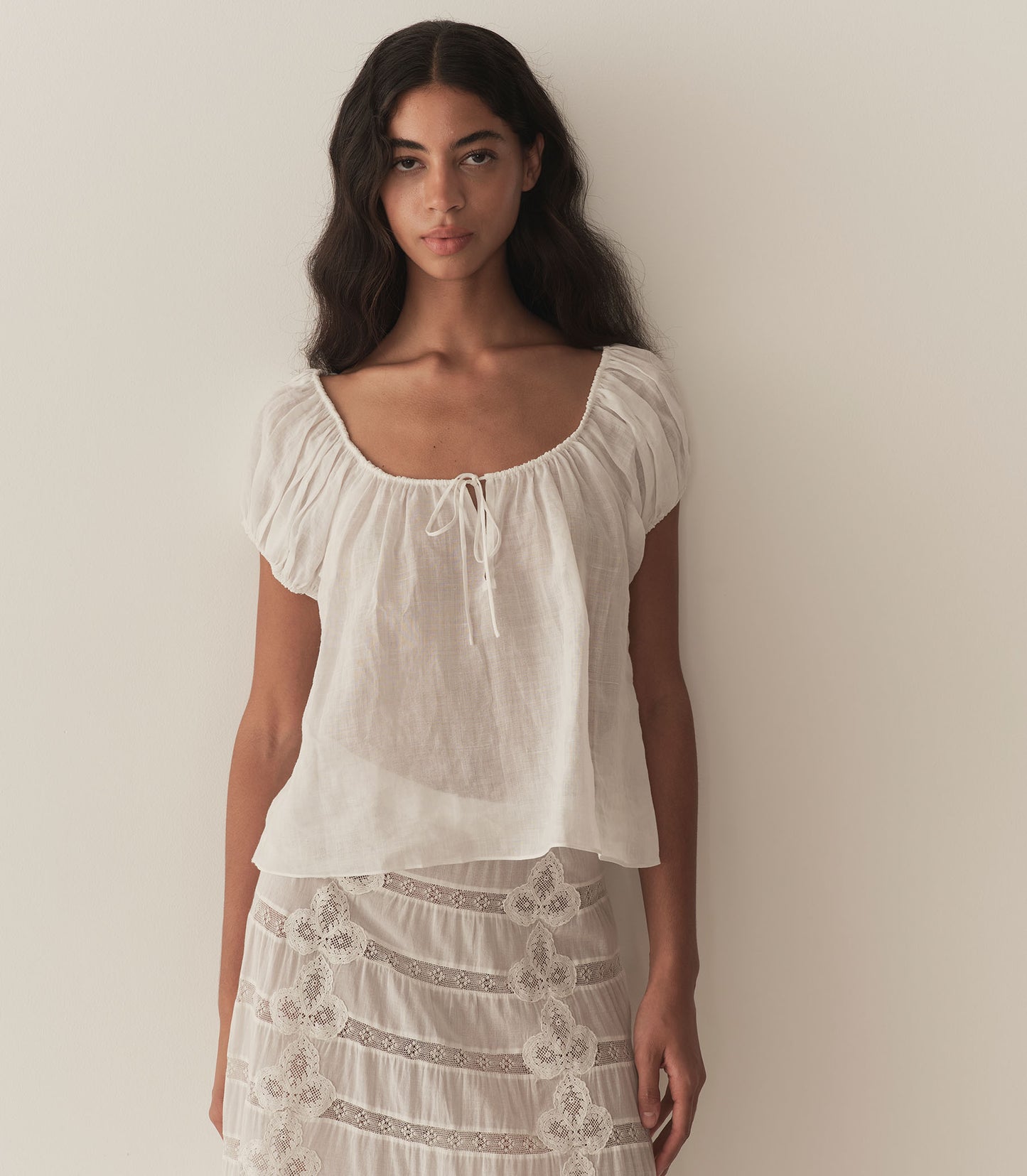 Rocio is wearing a white short puff sleeve blouse paired with a white maxi skirt.