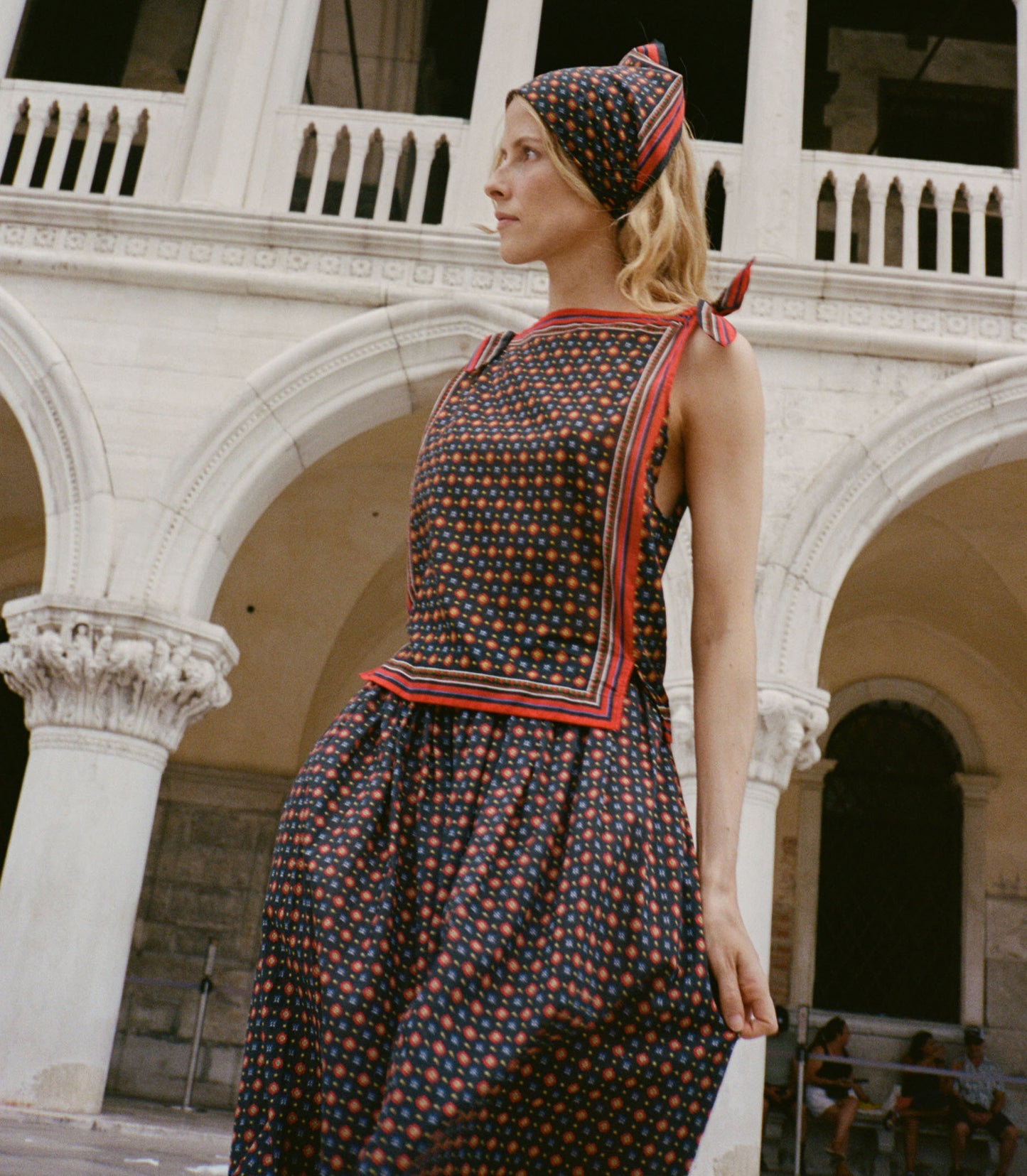 Woman in a patterned dress standing in front of a classical building.