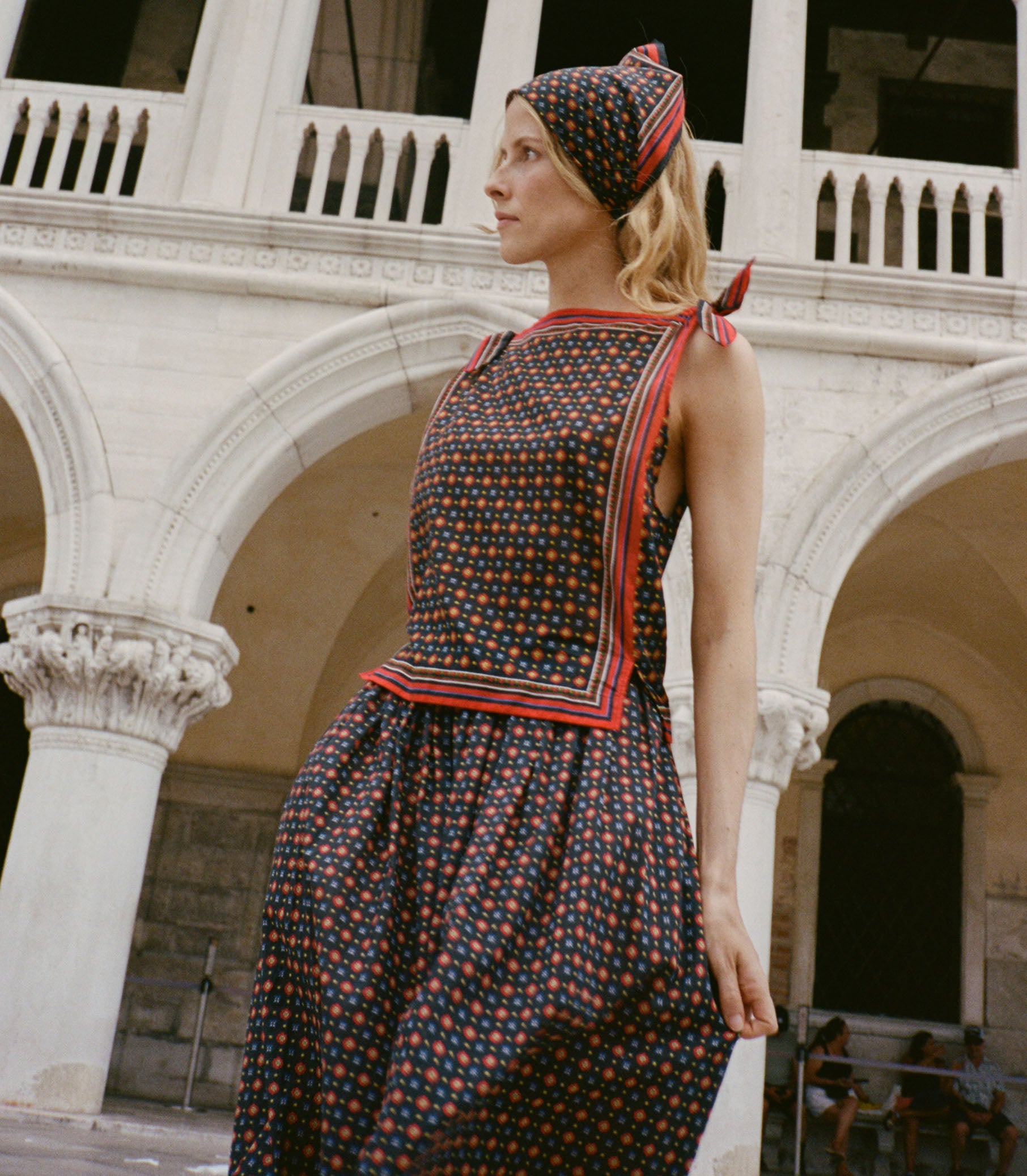 Woman in a patterned dress standing in front of a classical building. 1