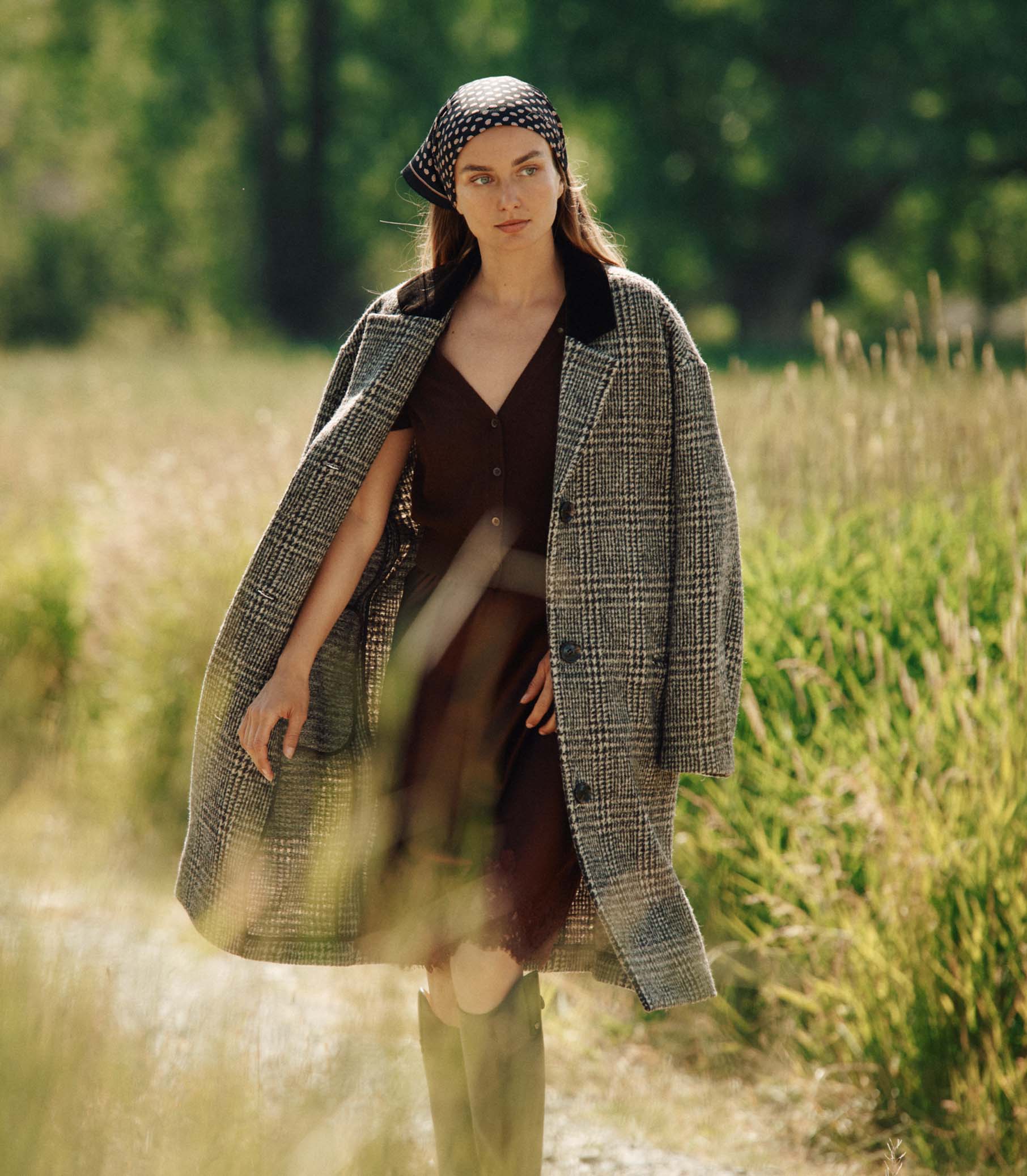 Woman in a plaid coat and headscarf standing in a field 4