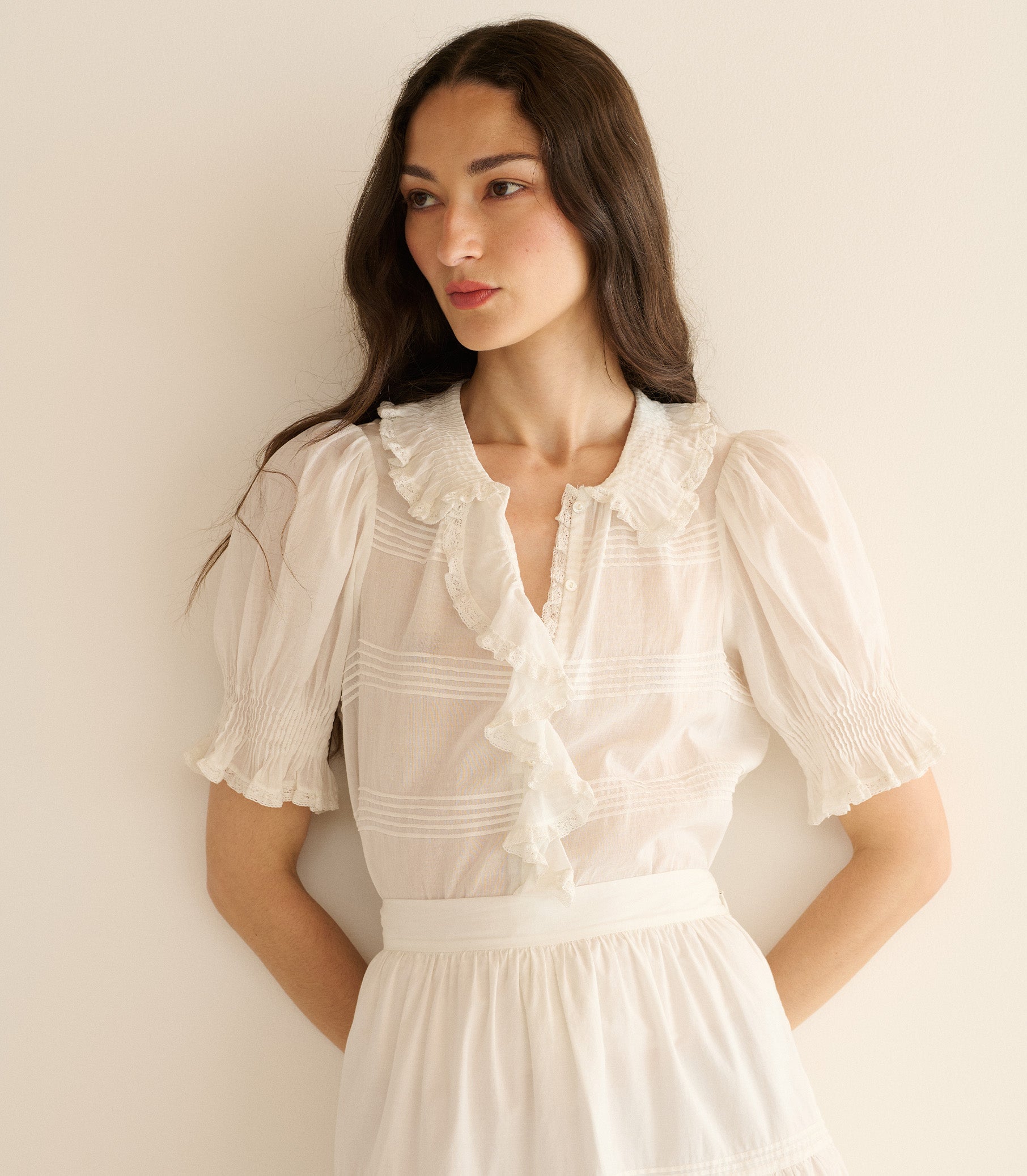 Woman wearing a white blouse against a plain background