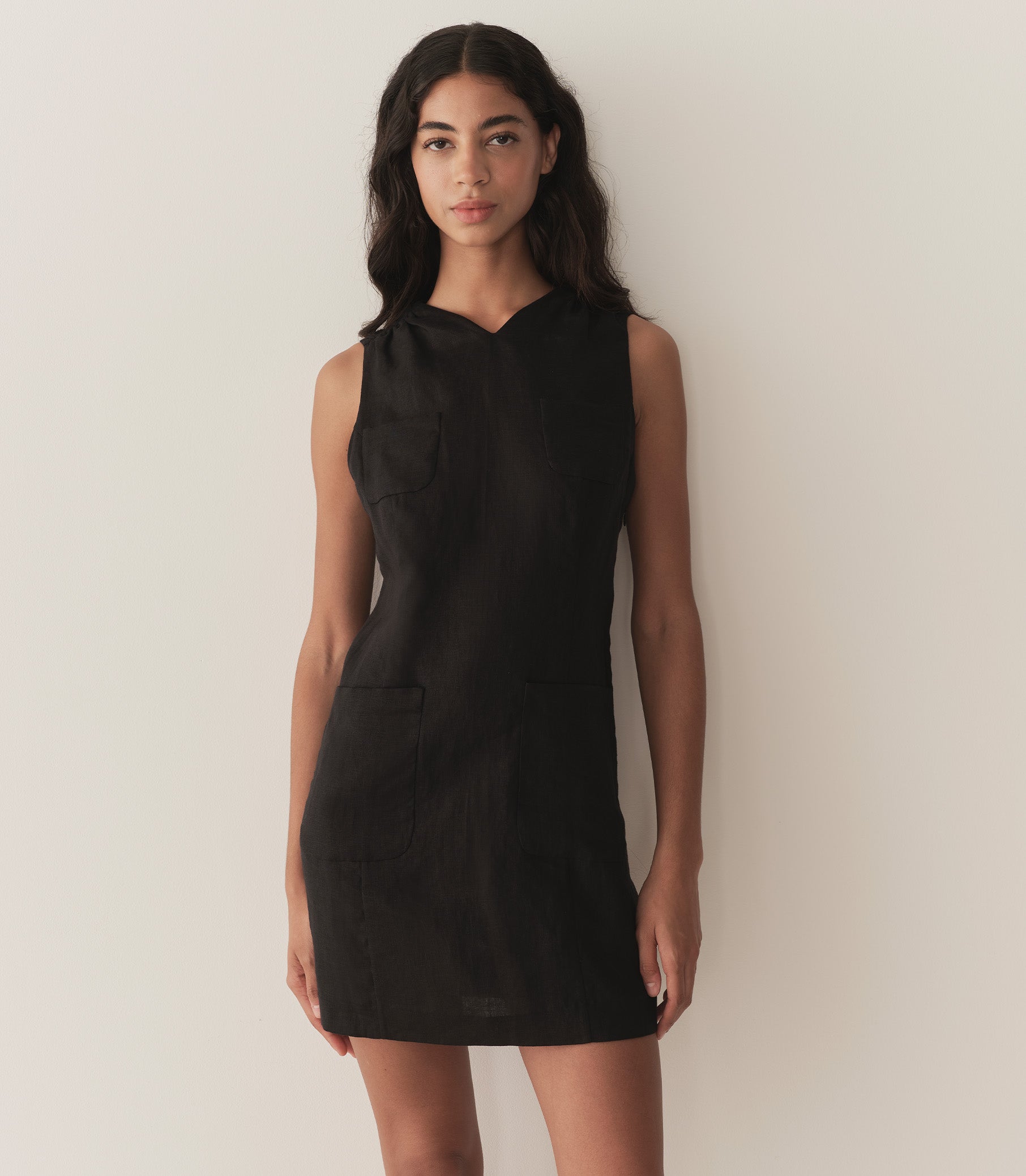 Rocio is wearing a black sleeveless linen mini dress.