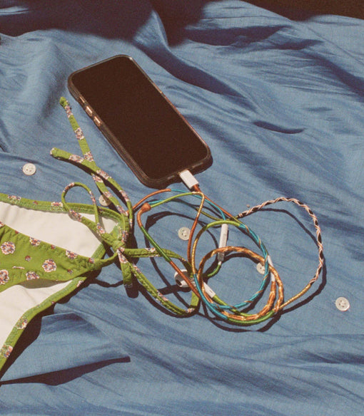 Phone with rainbow headphones on a blue fabric background