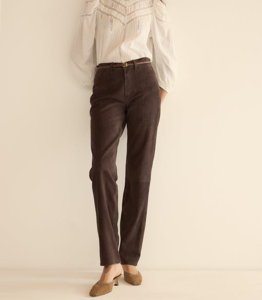 Brown pants worn with a white shirt on a plain background
