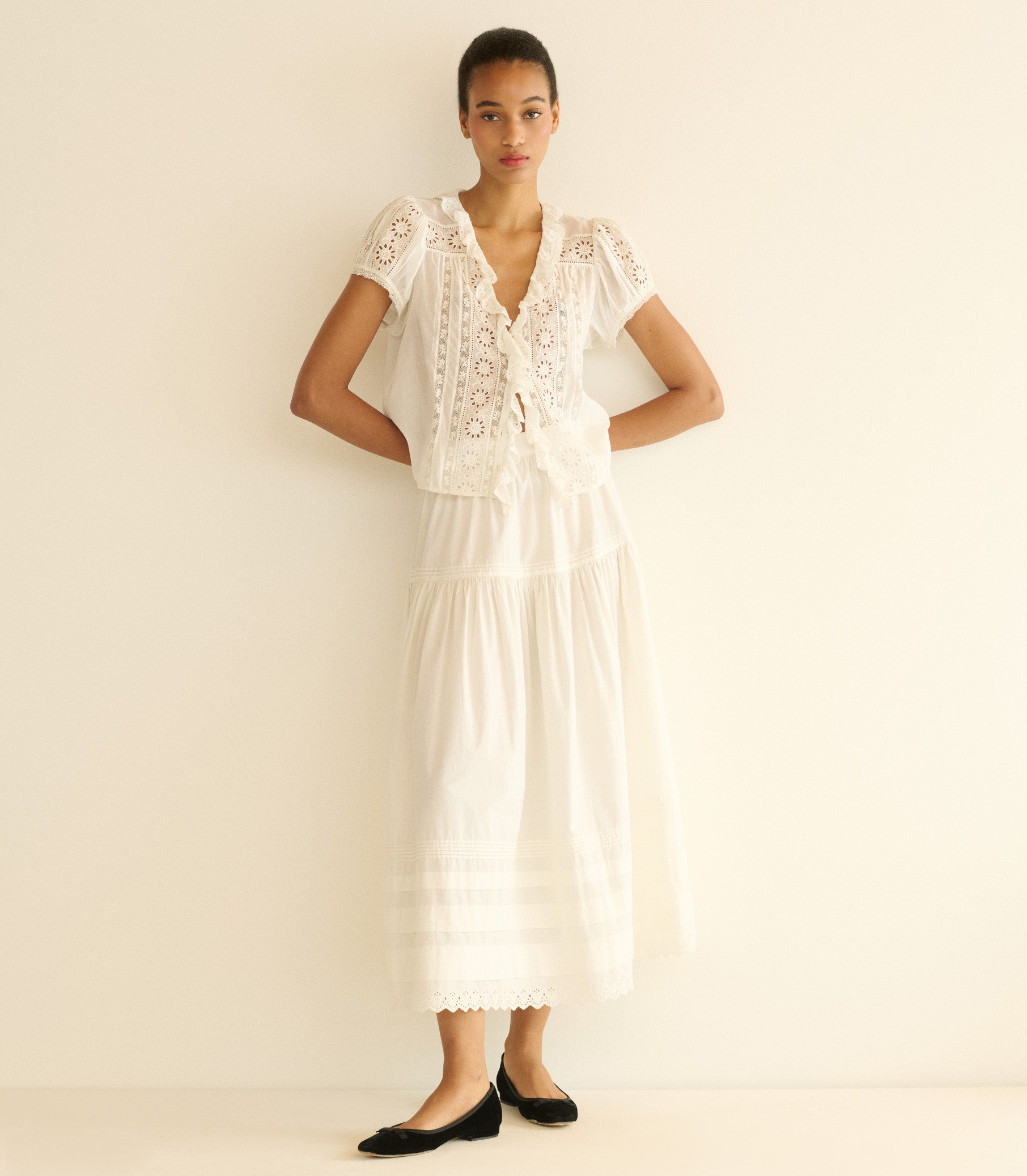 Woman wearing a white lace top and white skirt against a plain background 2
