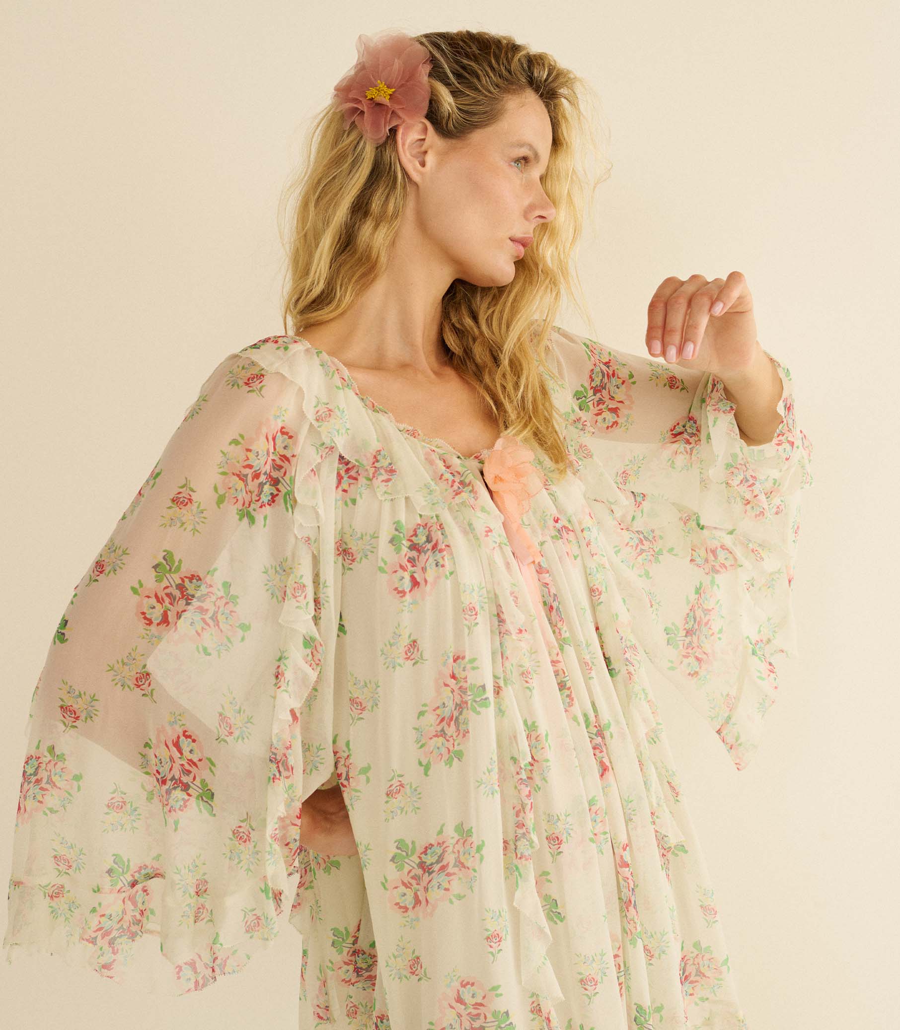 Woman wearing a white floral dress and pink floral barrette with a plain background 1
