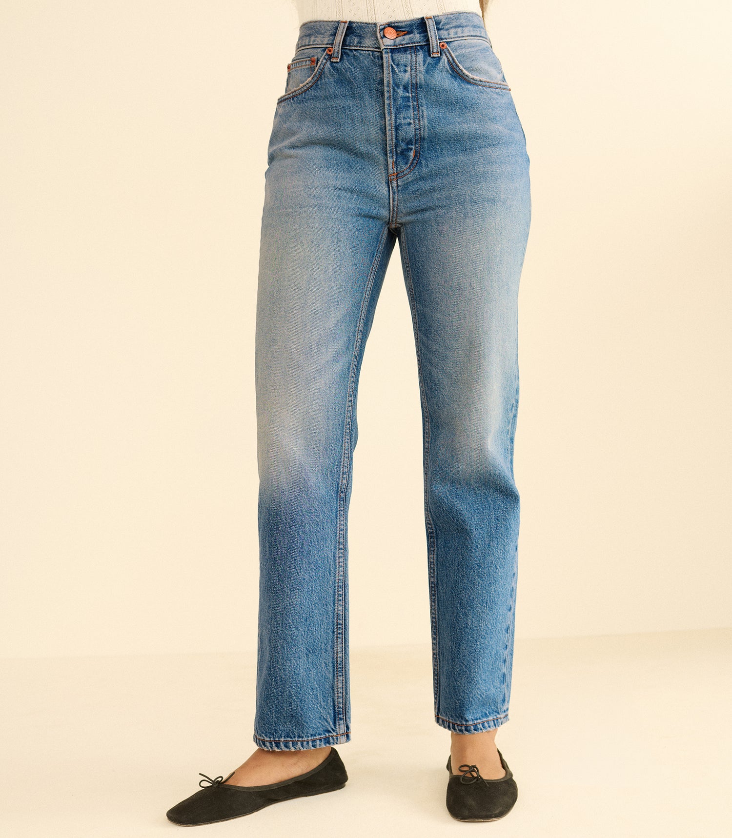 Blue jeans worn by a person on a beige background