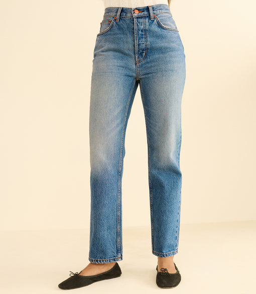 Blue jeans worn by a person on a beige background