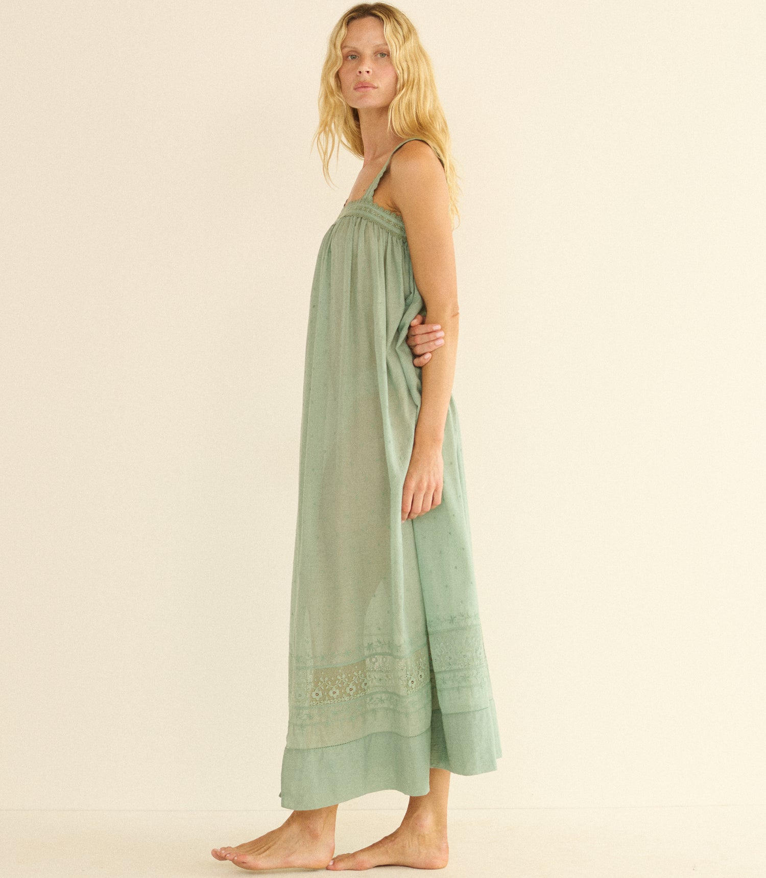 Woman wearing a green dress with embroidery on a beige background