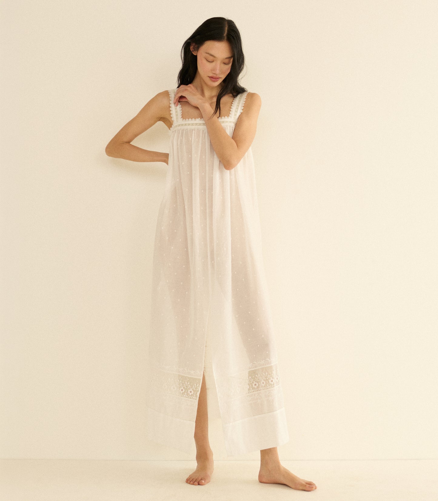Woman wearing a long, white dress against a plain background
