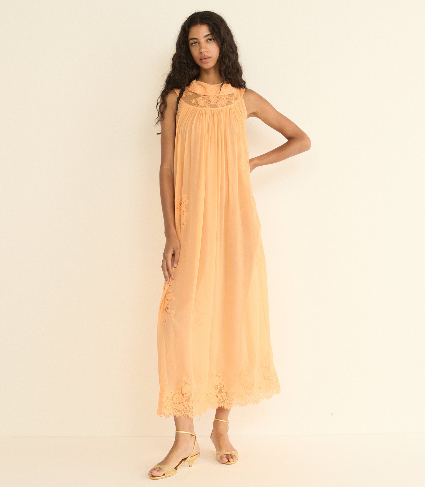 Woman wearing a peach-colored dress against a plain background
