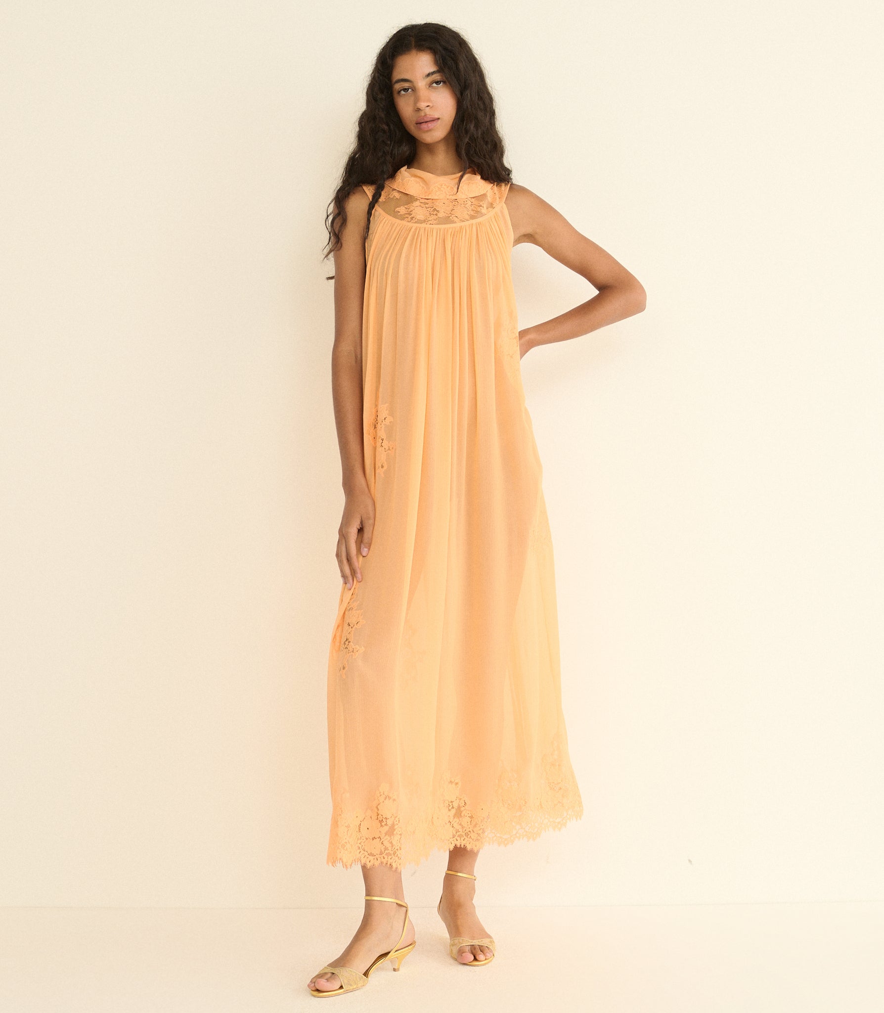 Woman wearing a peach-colored dress against a plain background 1
