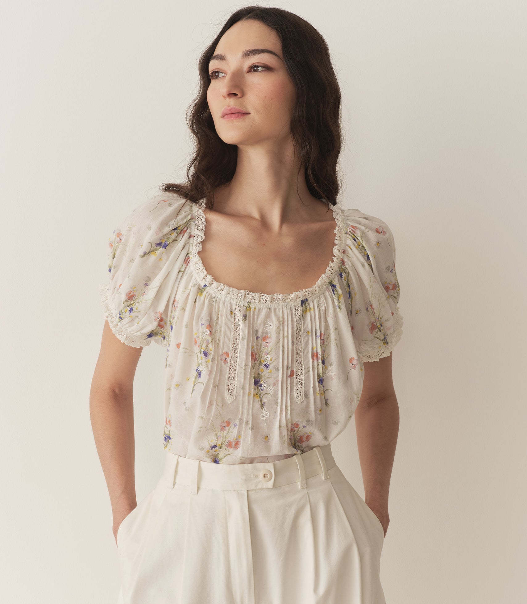 Bruna is wearing a white floral blouse with puff short sleeves.