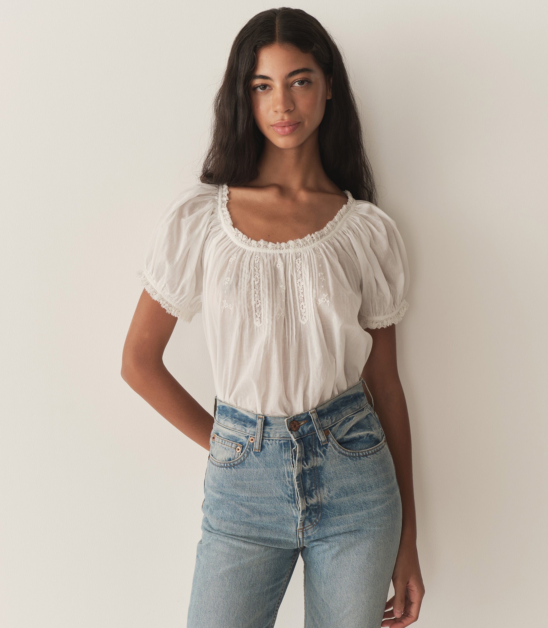 Rocio is wearing a white short puff sleeve blouse and denim jeans.