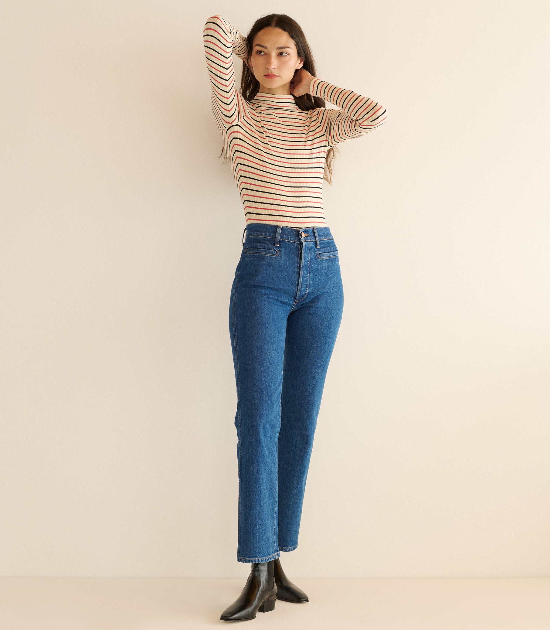 Woman wearing a striped sweater and blue jeans against a beige background 1