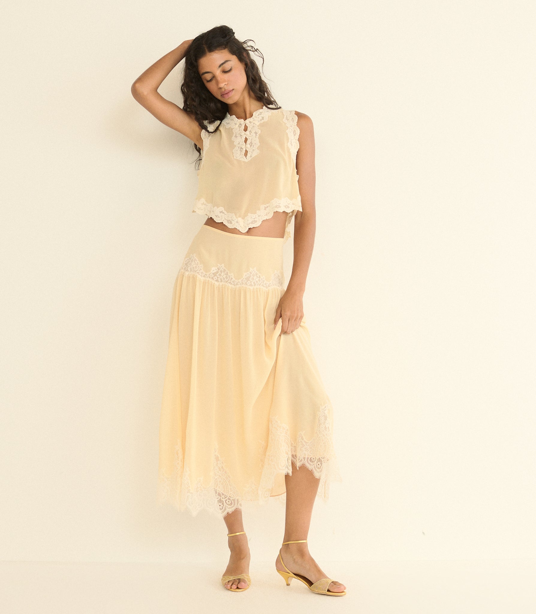 Woman wearing a light beige lace outfit against a plain background 1
