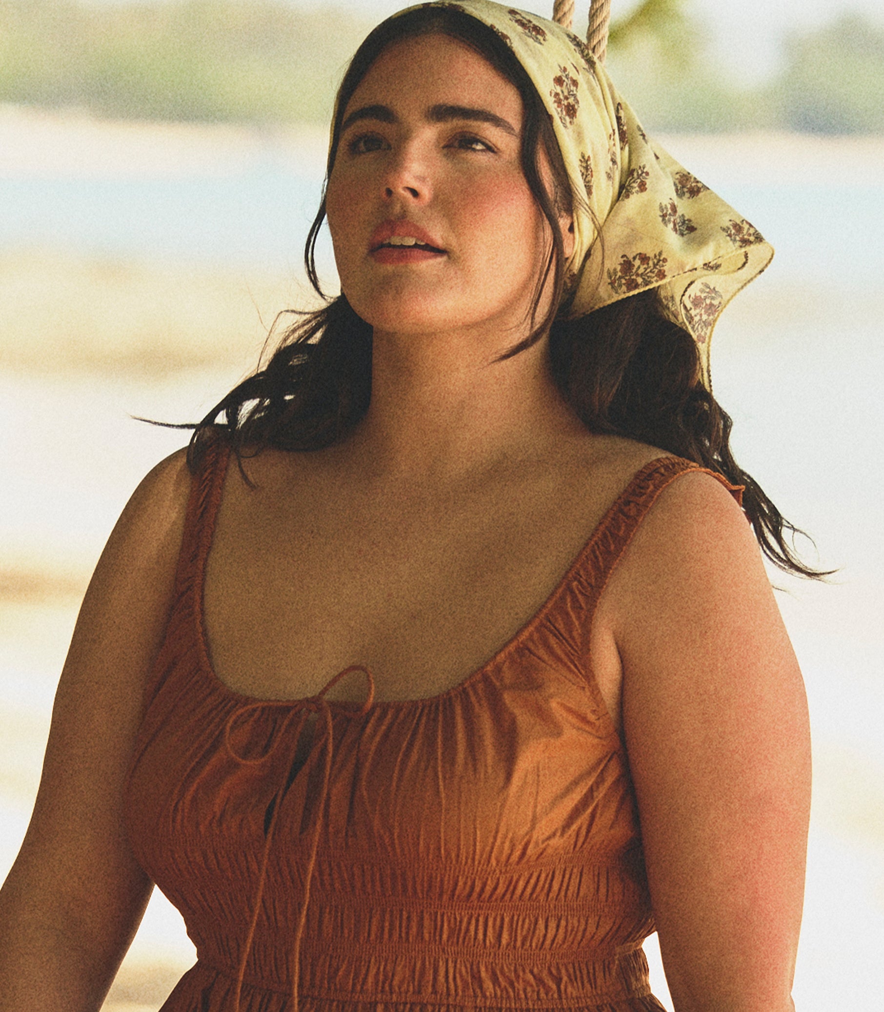 Woman wearing a printed headscarf and orange dress outdoors
